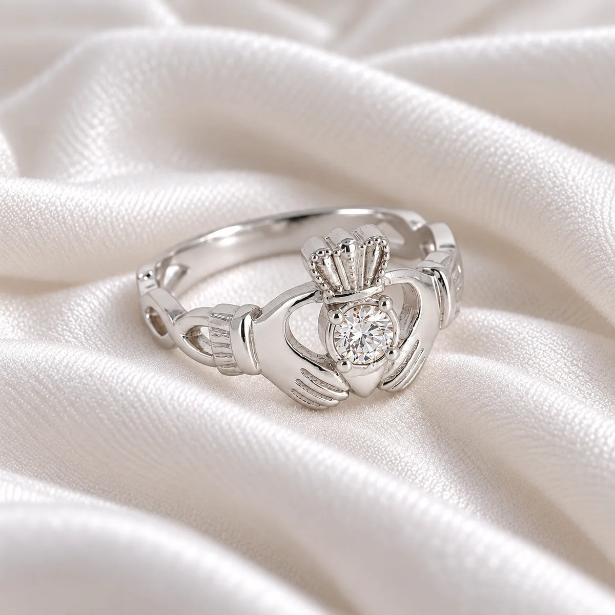 Claddagh_ring_in_sterling_silver_with_a_round_CZ_stone_at_side_angle_view_on_soft_fabric_background