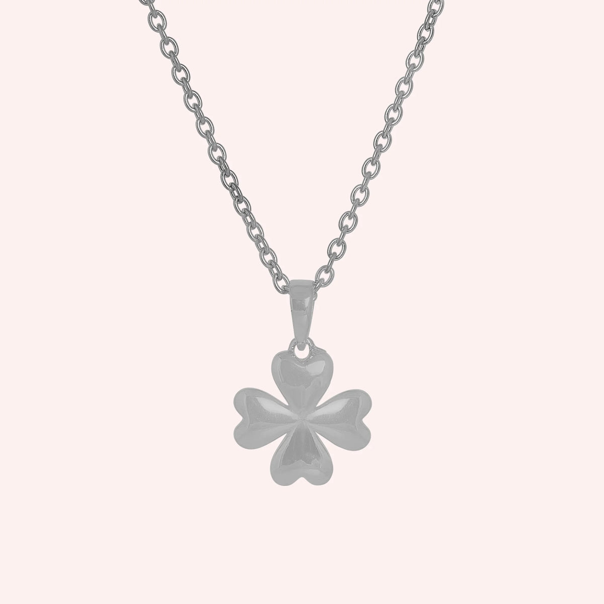 Clover_necklace_in_sterling_silver_with_four_leaves_design_at_front_angle_view_on_solid_pink_background