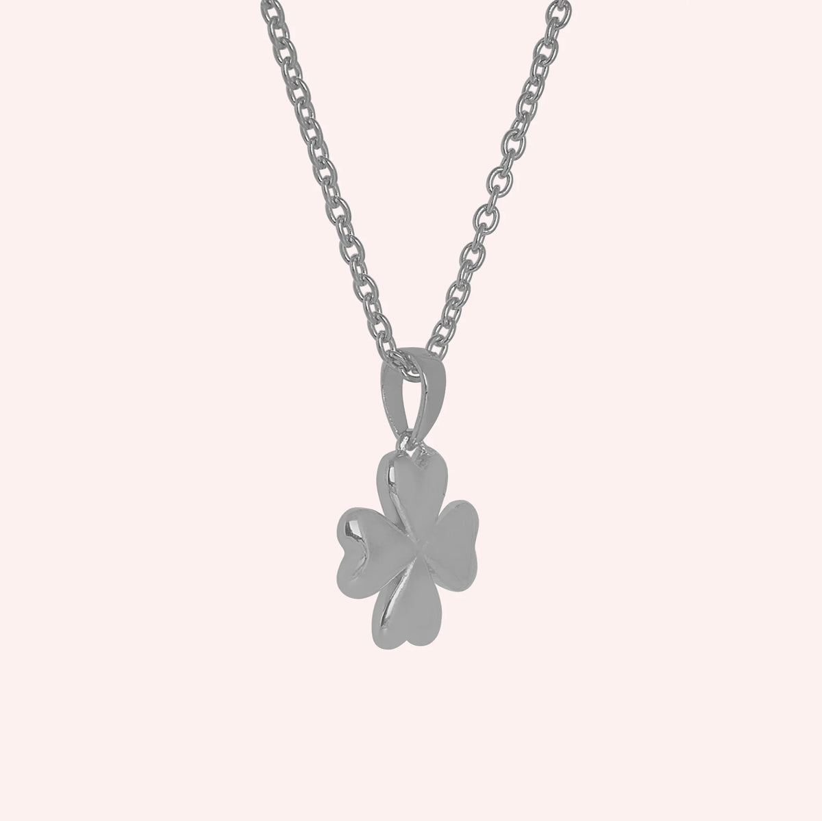 Clover_necklace_in_sterling_silver_with_four_leaves_design_at_slight_angle_view_on_solid_pink_background