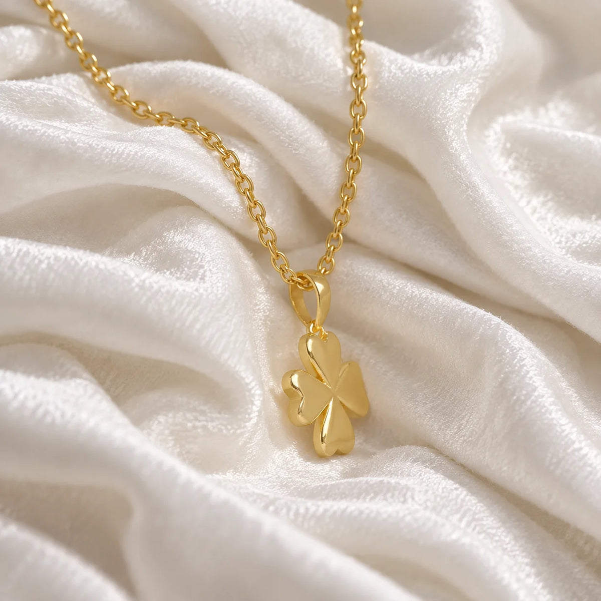 Clover_necklace_in_gold_plated_silver_with_four_leaves_design_at_slight_angle_view_on_soft_fabric_background