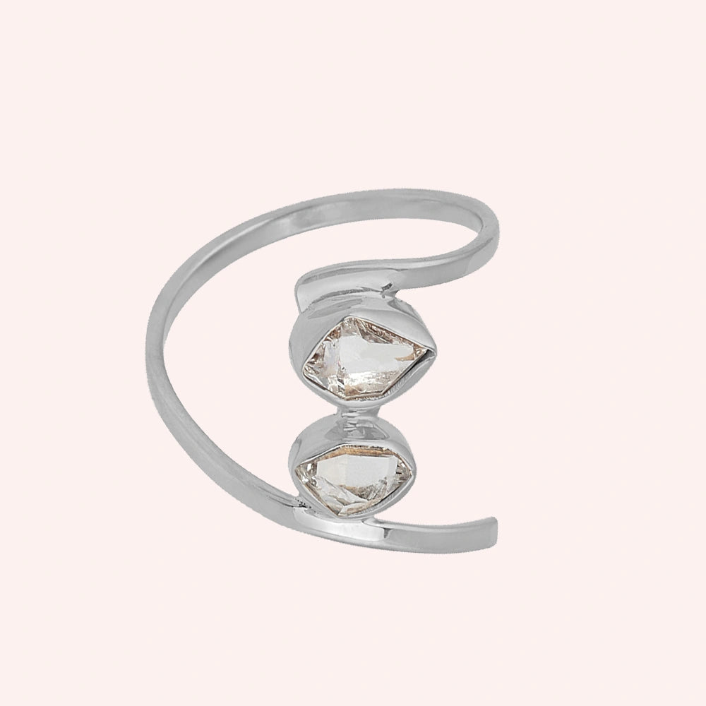 Cocktail_ring_with_open_sterling_silver_band_and_two_herkimer_stones_shown_at_front_angle_on_solid_pink_background