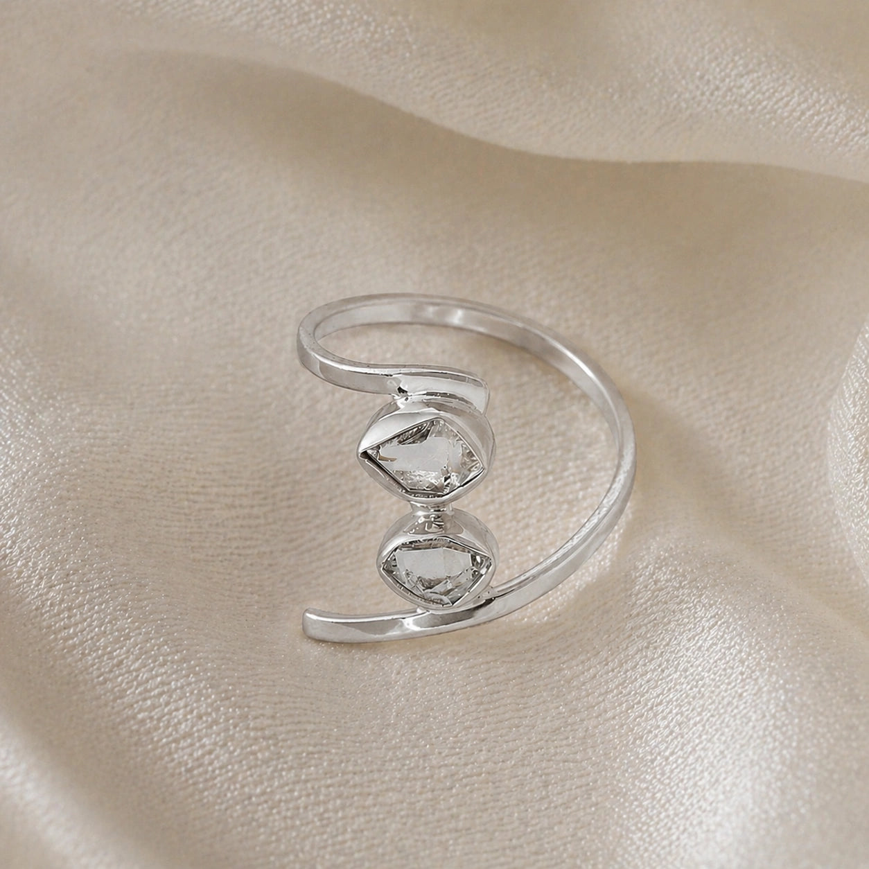 Cocktail_ring_with_open_sterling_silver_band_and_two_herkimer_stones_shown_at_front_angle_on_soft_fabric_background
