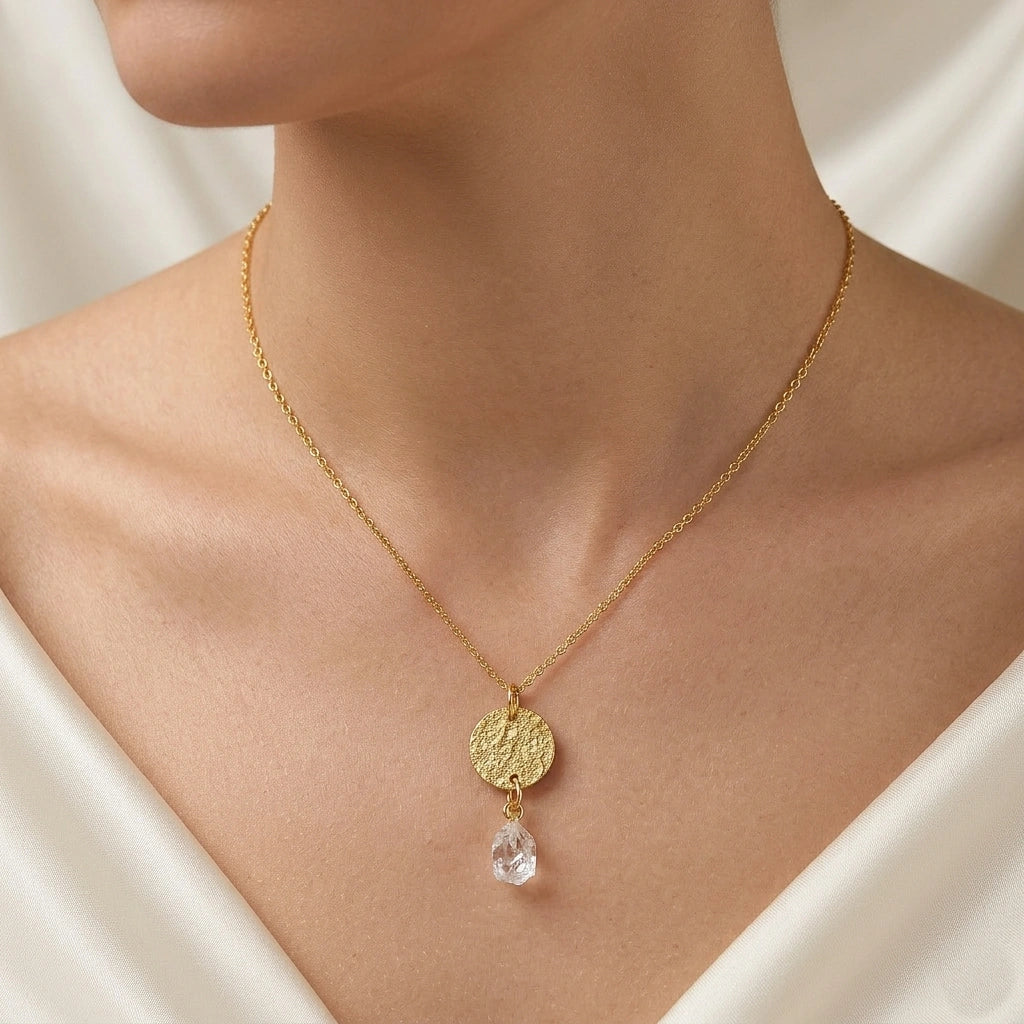 Coin_necklace_in_front_angled_view_with_textured_round_pendant_gold_plated_silver_and_herkimer_stone_worn_by_a_model
