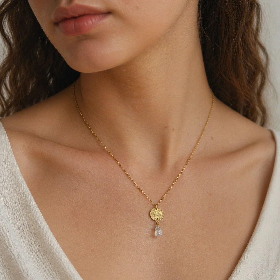 Coin_necklace_in_front_angled_view_with_textured_round_pendant_gold_plated_silver_and_herkimer_stone_on_soft_fabric_background