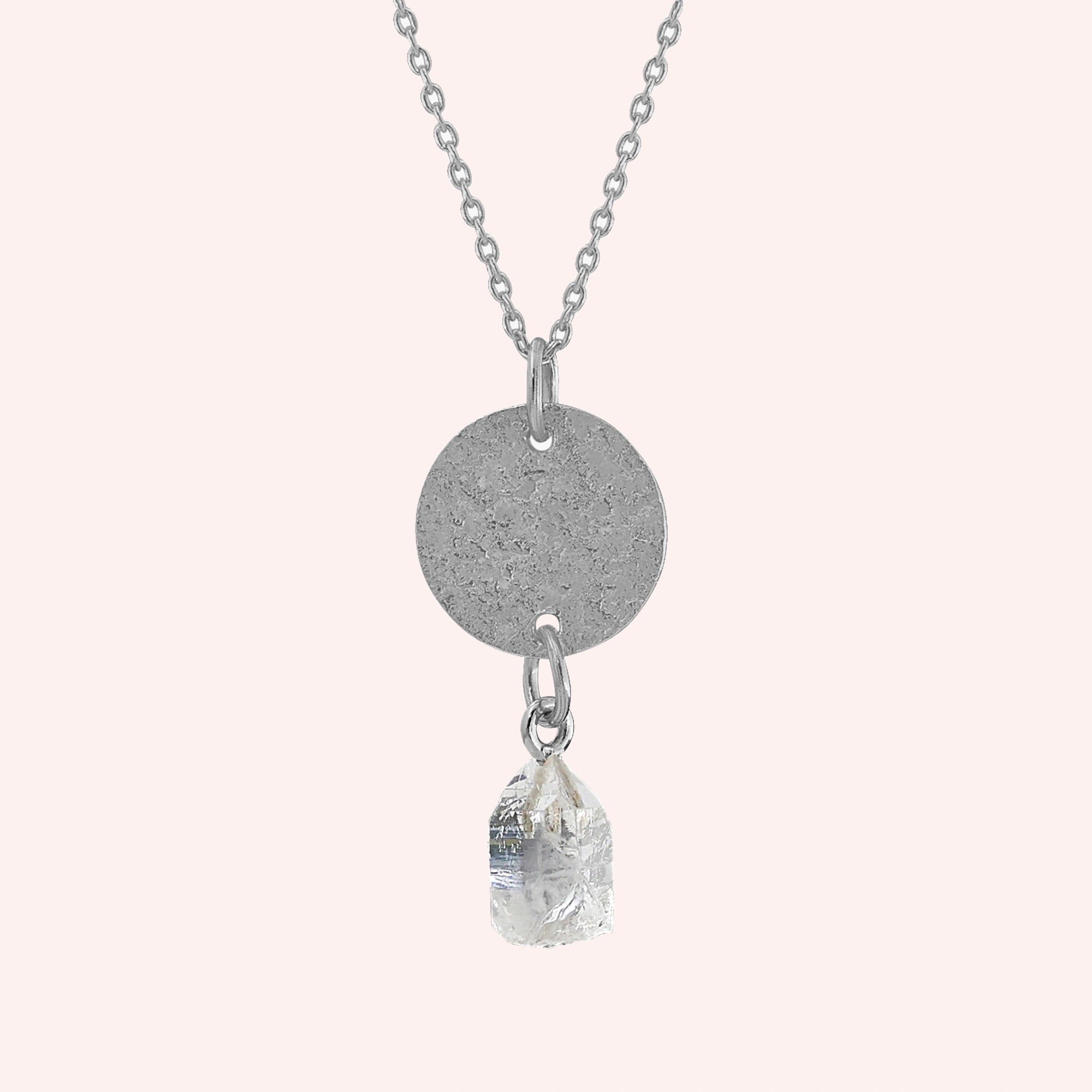Coin_necklace_in_front_angled_view_with_textured_round_pendant_sterling_silver_and_herkimer_stone_on_solid_pink_background