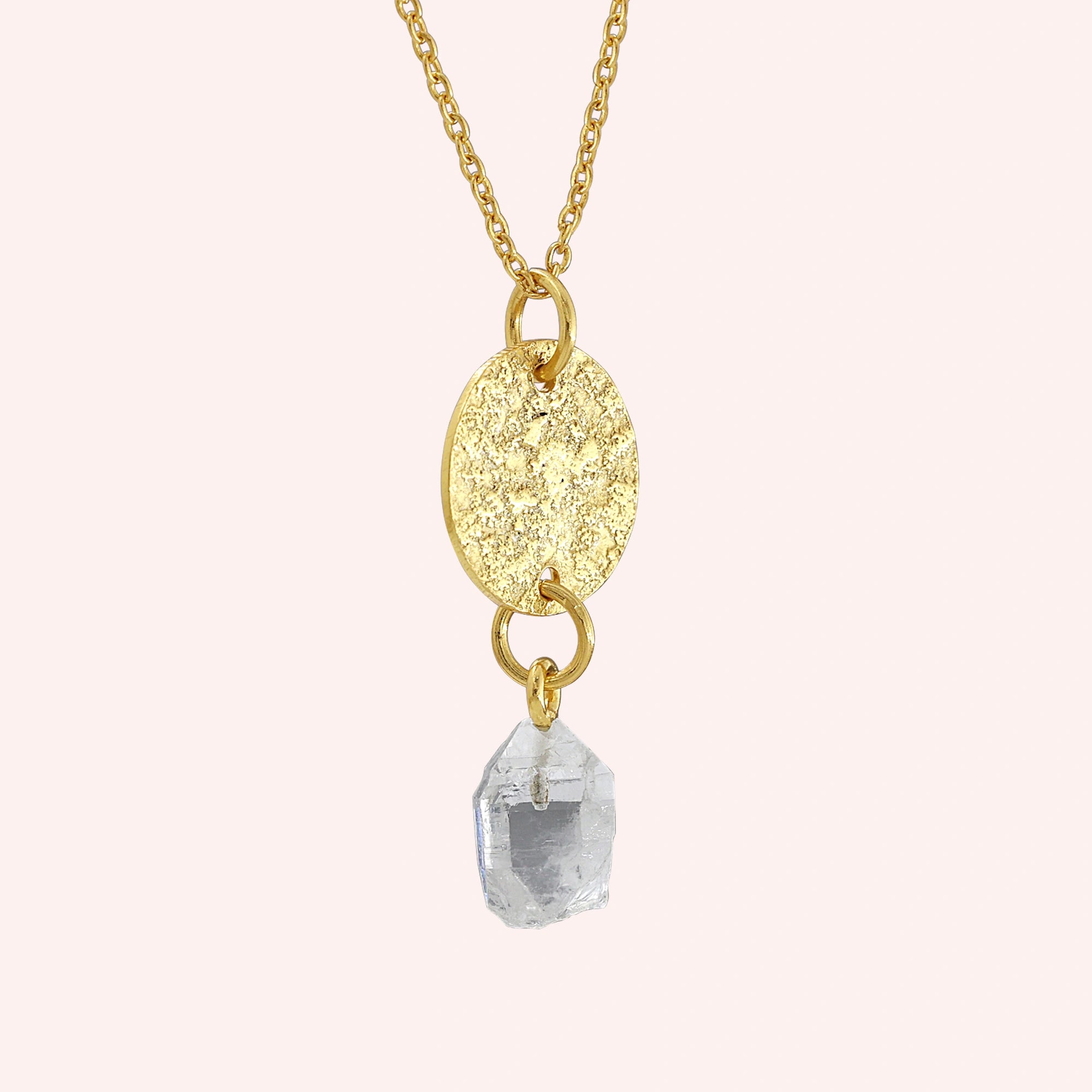 Coin_necklace_in_slight_angled_view_with_textured_round_pendant_gold_plated_silver_and_herkimer_stone_on_solid_pink_background