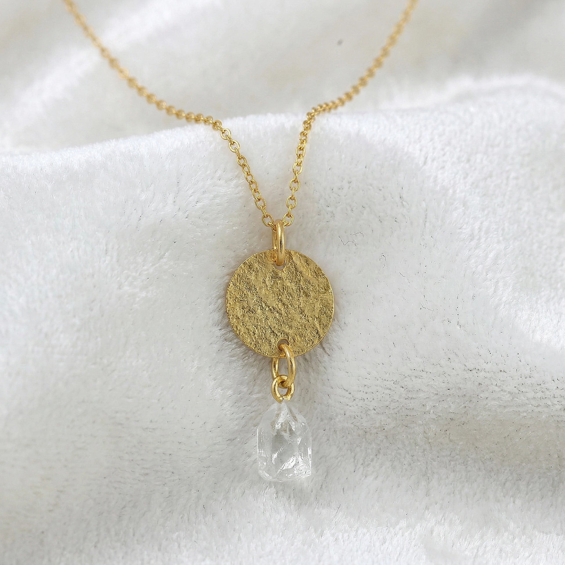 Coin_necklace_in_front_angled_view_with_textured_round_pendant_gold_plated_silver_and_herkimer_stone_on_soft_fabric_background