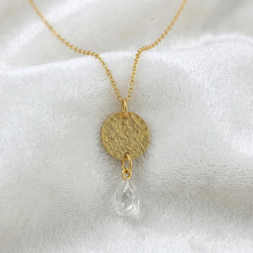 Coin_necklace_in_front_angled_view_with_textured_round_pendant_gold_plated_silver_and_herkimer_stone_on_soft_fabric_background