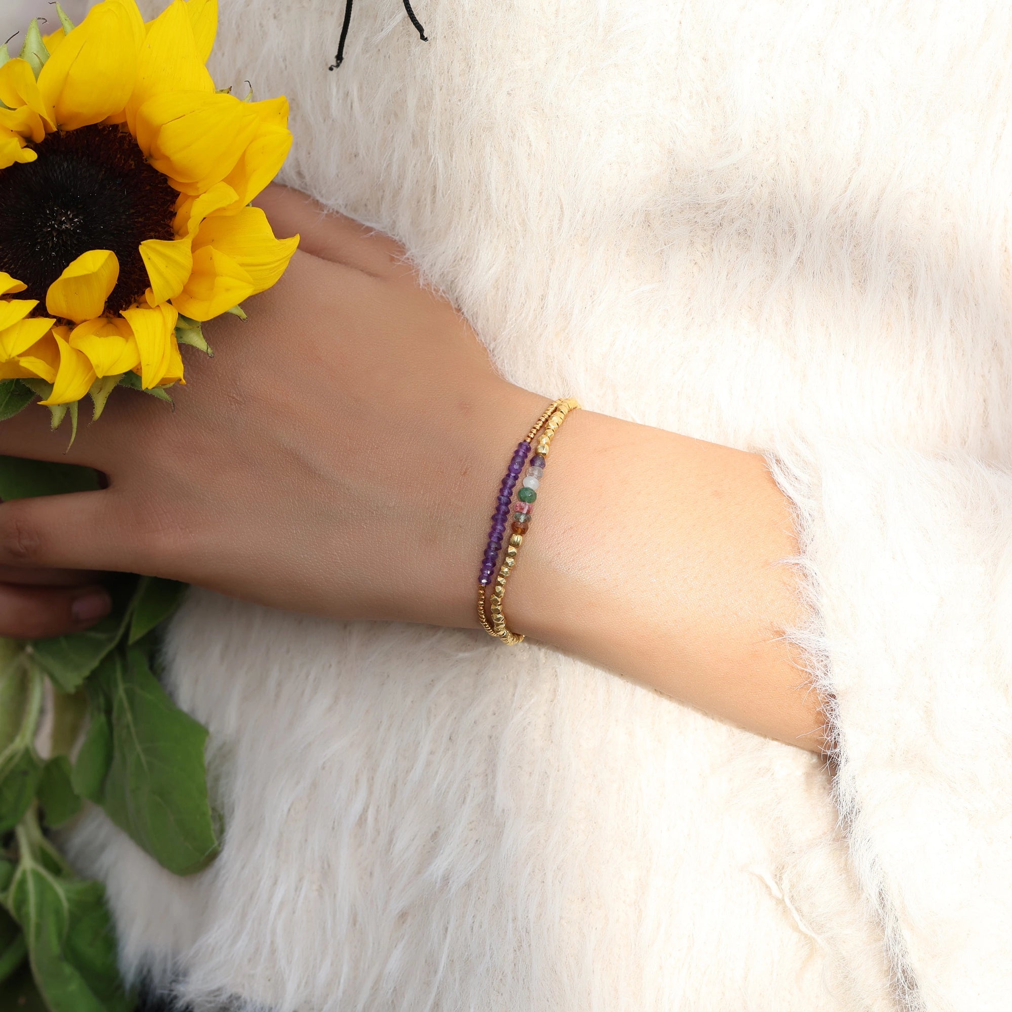 side_angle_colorful_beaded_bracelet_multi_gemstone_bracelet_gold_plated_on_wrist_with_sunflower_and_soft_fur_background