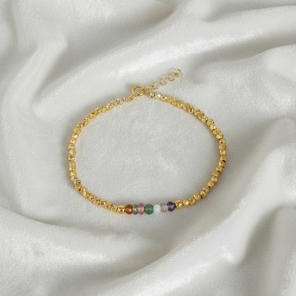 top_angle_colorful_beaded_bracelet_multi_gemstone_bracelet_gold_plated_beads_with_rainbow_stones_on_soft_white_fabric