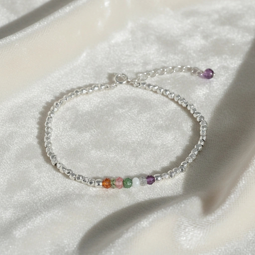 top_angle_colorful_beaded_bracelet_multi_gemstone_bracelet_silver_chain_with_rainbow_beads_on_soft_white_fabric_background