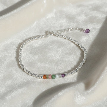 top_angle_colorful_beaded_bracelet_multi_gemstone_bracelet_silver_chain_with_rainbow_beads_on_soft_white_fabric_background