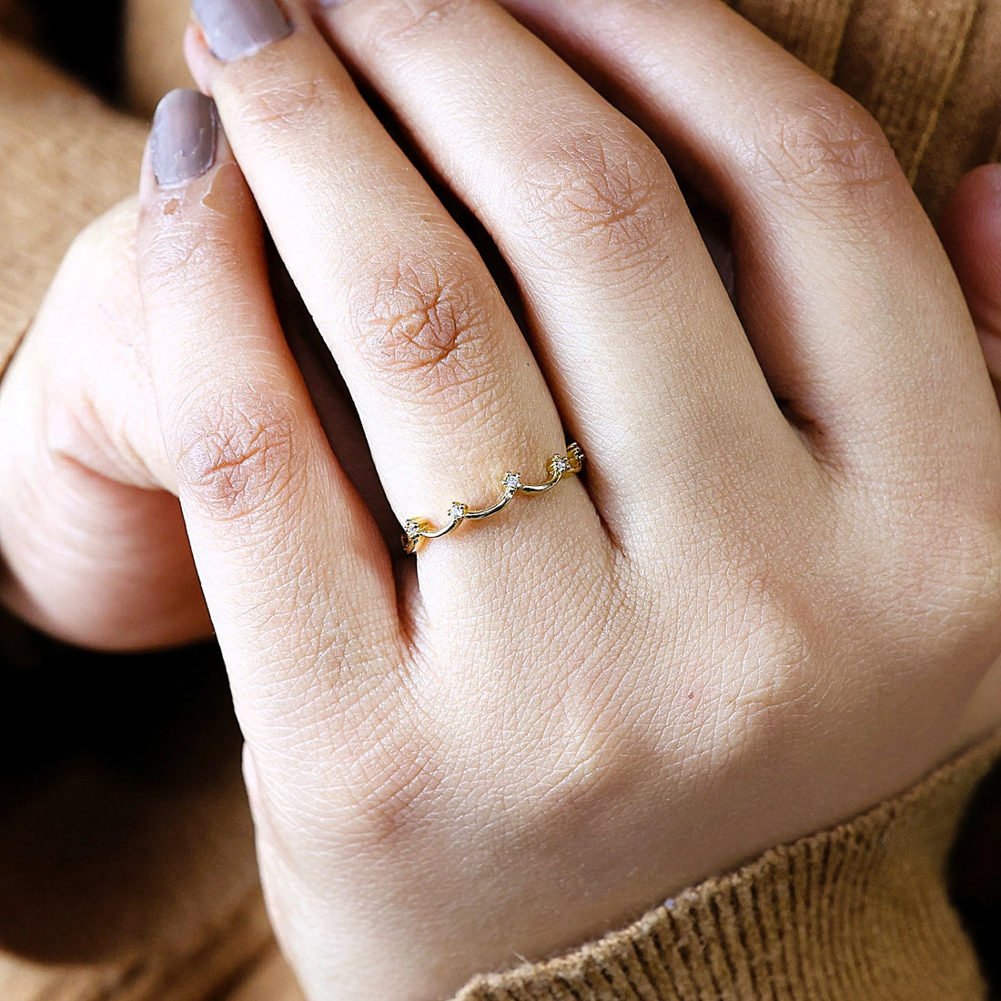 A sterling silver crown ring featuring white topaz stones and a tiara ring design at a side angle on a white fabric background