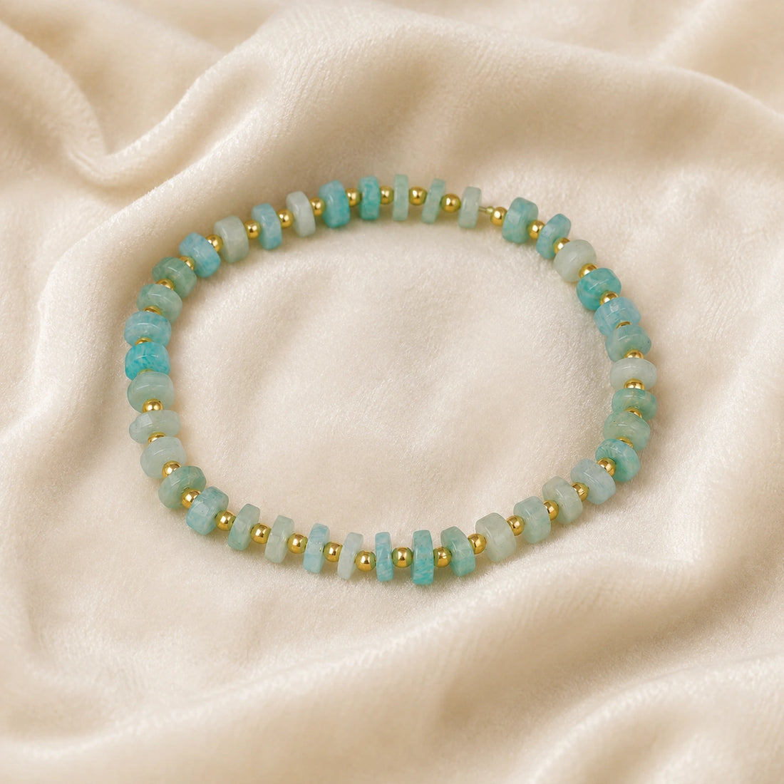Crystal_bead_bracelet_with_amazonite_stones_and_gold_plated_silver_beads_at_front_angle_view_on_soft_fabric_background
