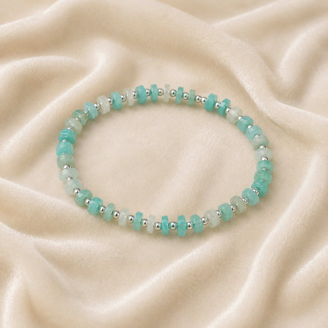 Crystal_bead_bracelet_with_amazonite_stones_and_sterling_silver_beads_at_front_angle_view_on_soft_fabric_background