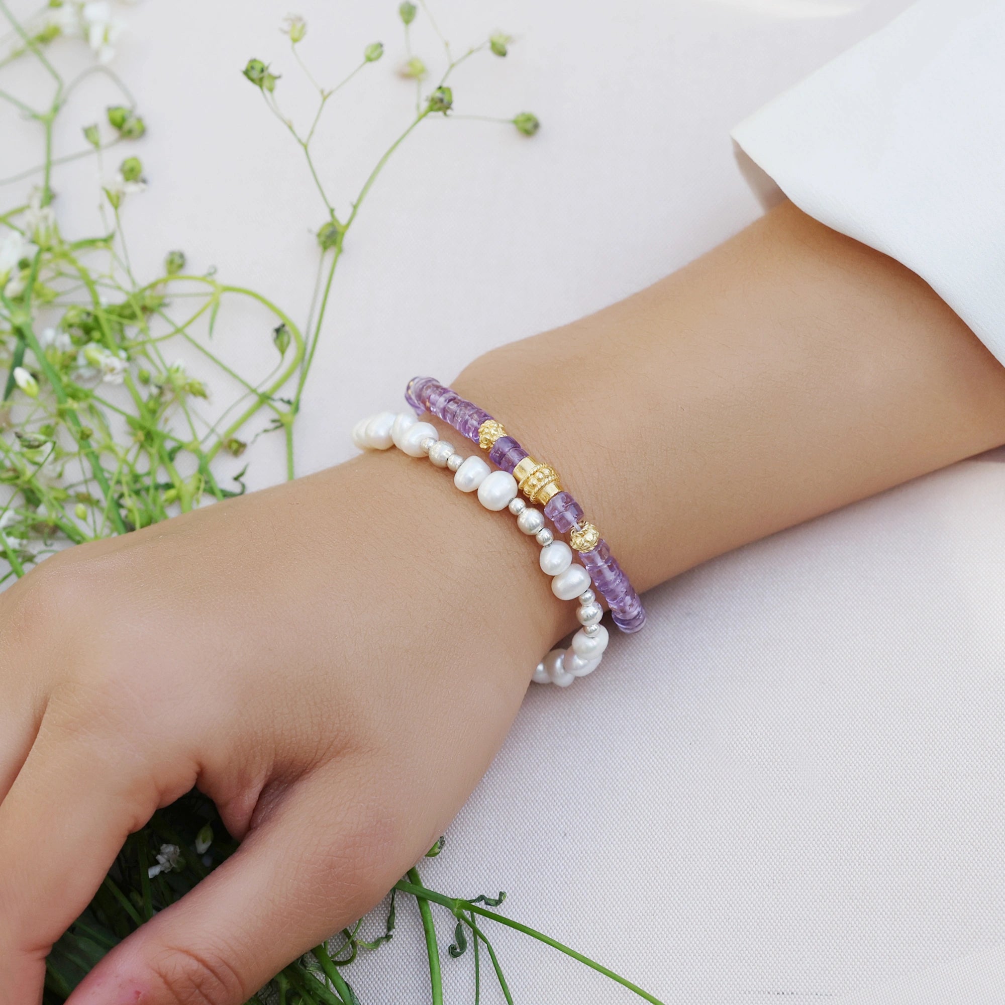 side_angle_crystal_bracelet_with_amethyst_beads_and_gold_plated_accents_worn_on_hand_over_soft_white_background