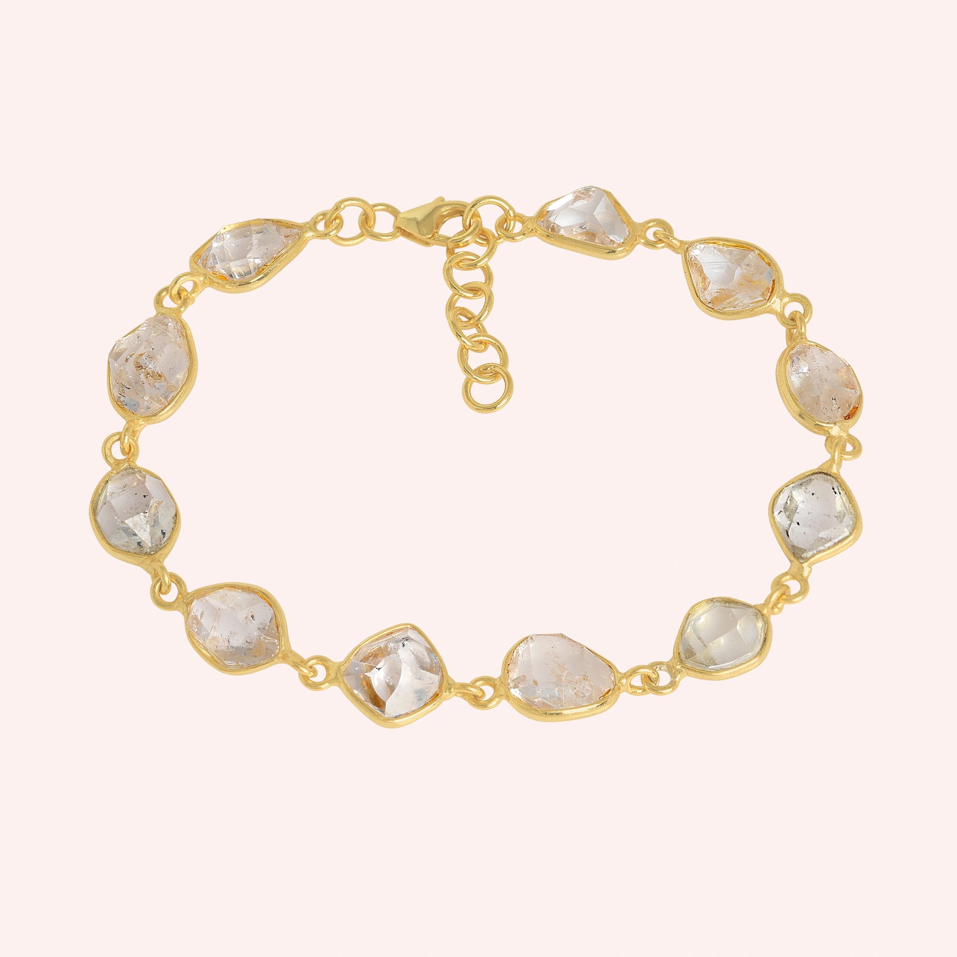 Crystal_bracelet_in_gold_plated_silver_with_raw_herkimer_stones_at_front_angle_view_on_solid_pink_background