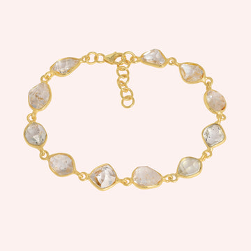 Crystal_bracelet_in_gold_plated_silver_with_raw_herkimer_stones_at_front_angle_view_on_solid_pink_background