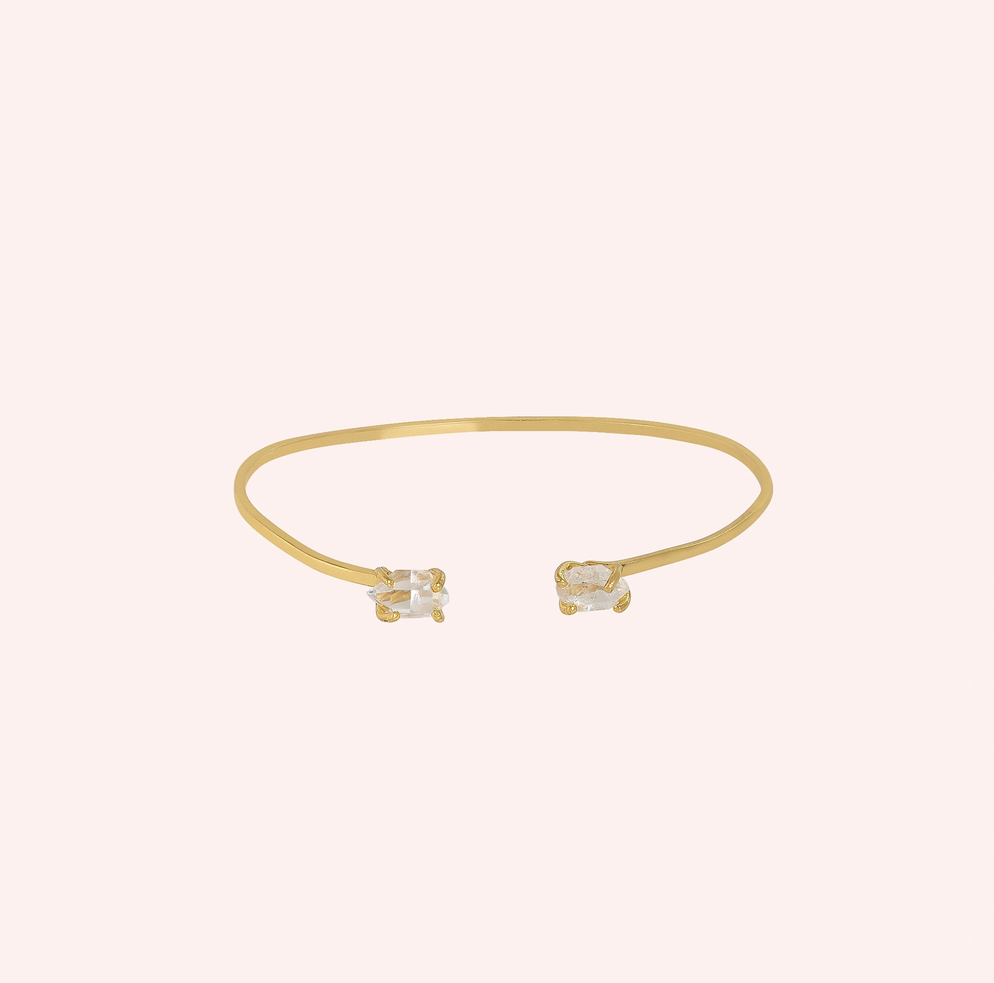 Crystal_bracelet_in_gold_plated_silver_with_two_raw_herkimer_stones_at_front_angle_view_on_solid_pink_background