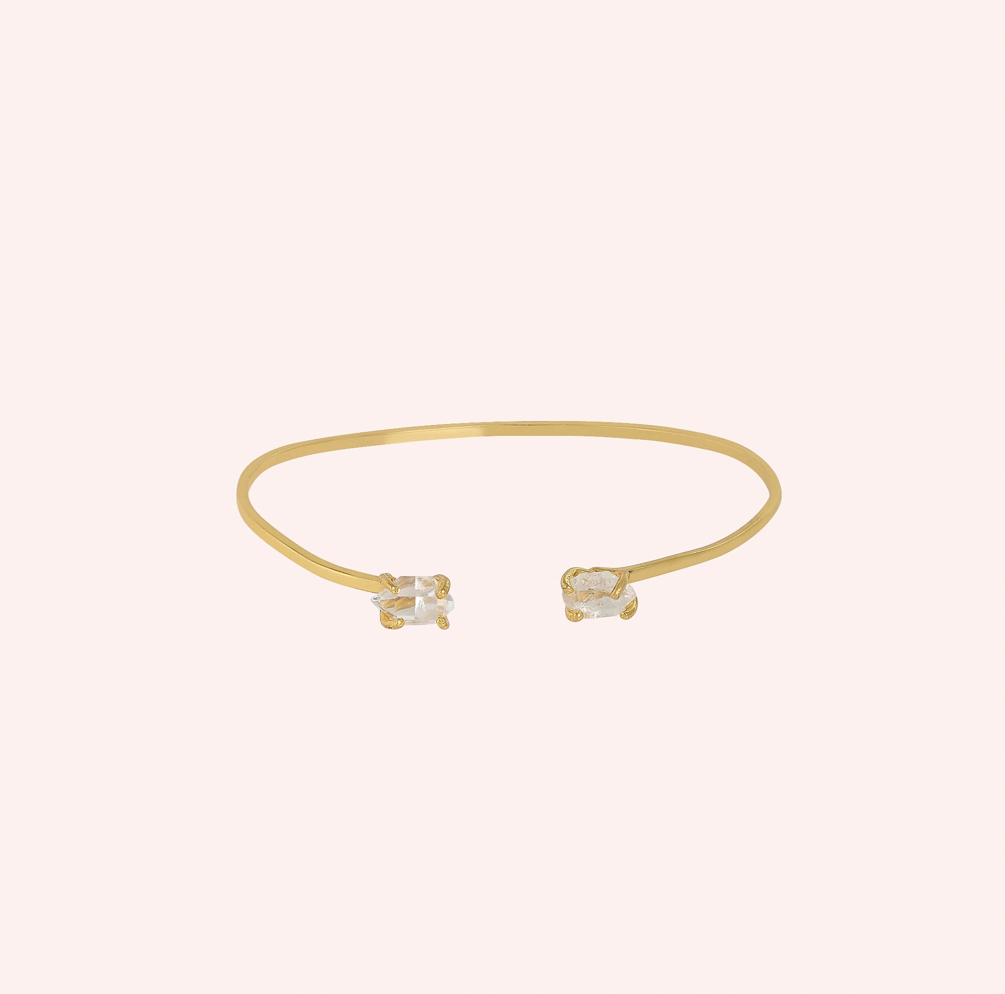 Crystal_bracelet_in_gold_plated_silver_with_two_raw_herkimer_stones_at_front_angle_view_on_solid_pink_background