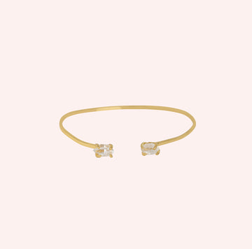 Crystal_bracelet_in_gold_plated_silver_with_two_raw_herkimer_stones_at_front_angle_view_on_solid_pink_background