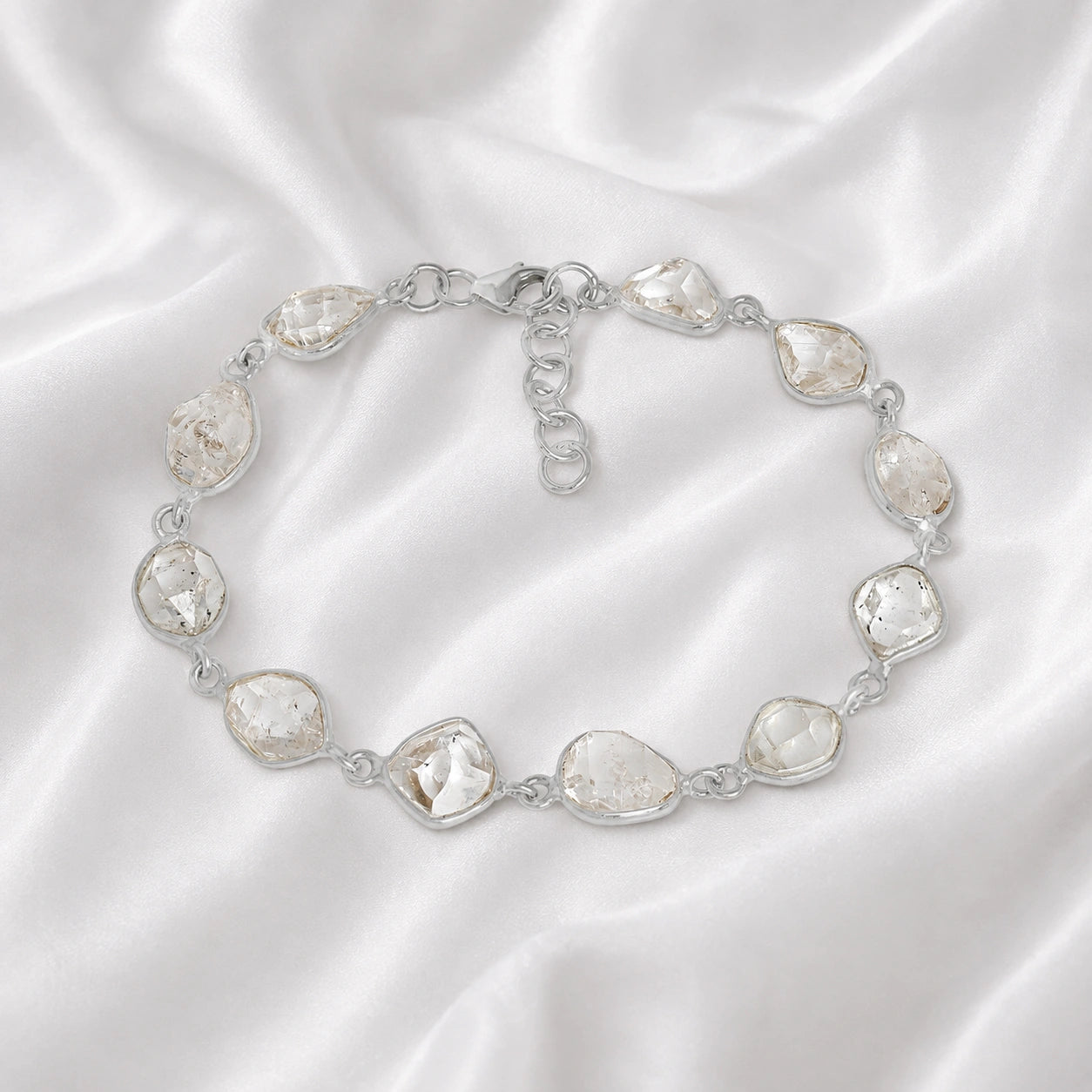 Crystal_bracelet_in_sterling_silver_with_raw_herkimer_stones_at_front_angle_view_on_soft_fabric_background