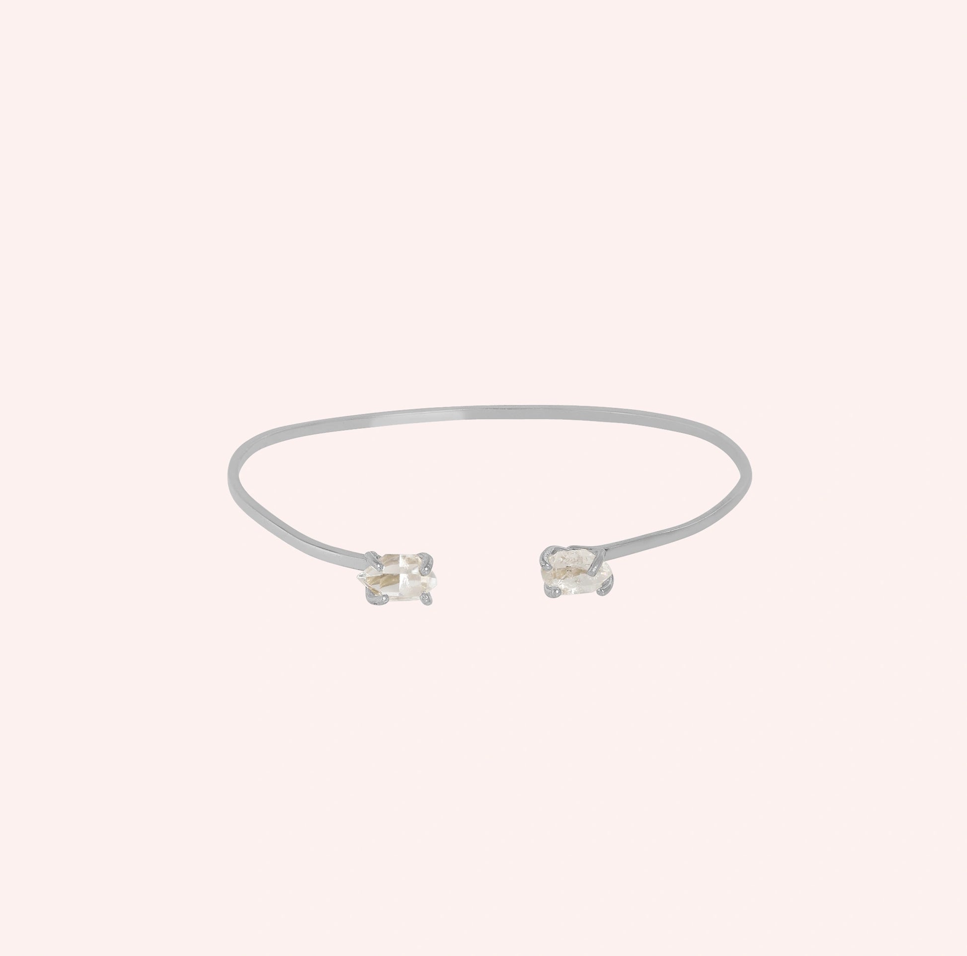 Crystal_bracelet_in_sterling_silver_with_two_raw_herkimer_stones_at_front_angle_view_on_solid_pink_background
