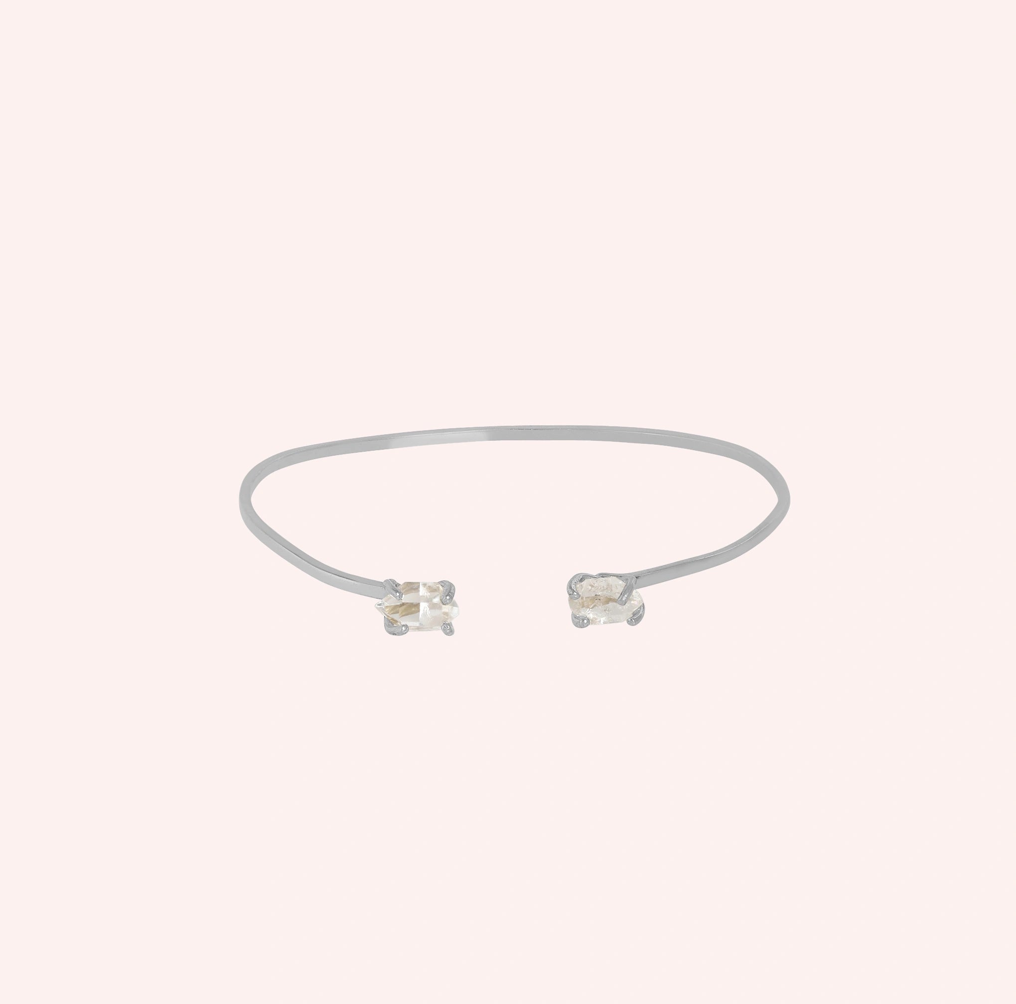 Crystal_bracelet_in_sterling_silver_with_two_raw_herkimer_stones_at_front_angle_view_on_solid_pink_background