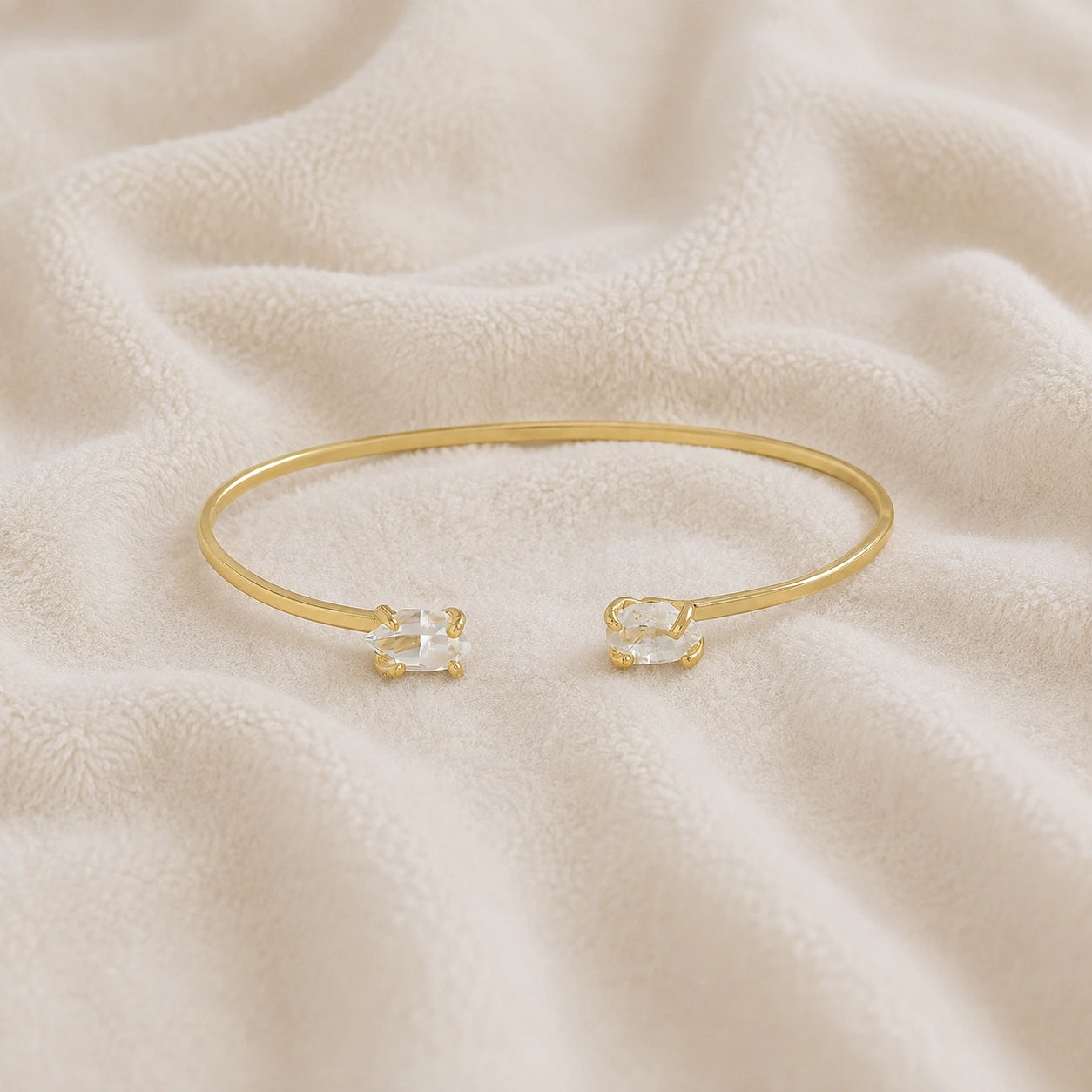 Crystal_bracelet_in_gold_plated_silver_with_two_raw_herkimer_stones_at_front_angle_view_on_soft_fabric_background