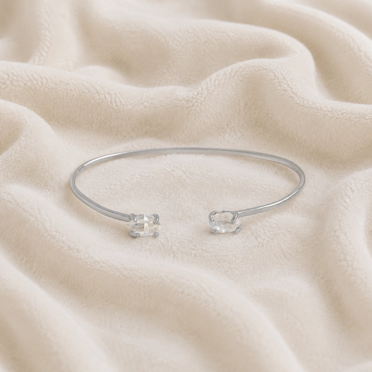Crystal_bracelet_in_sterling_silver_with_two_raw_herkimer_stones_at_front_angle_view_on_soft_fabric_background