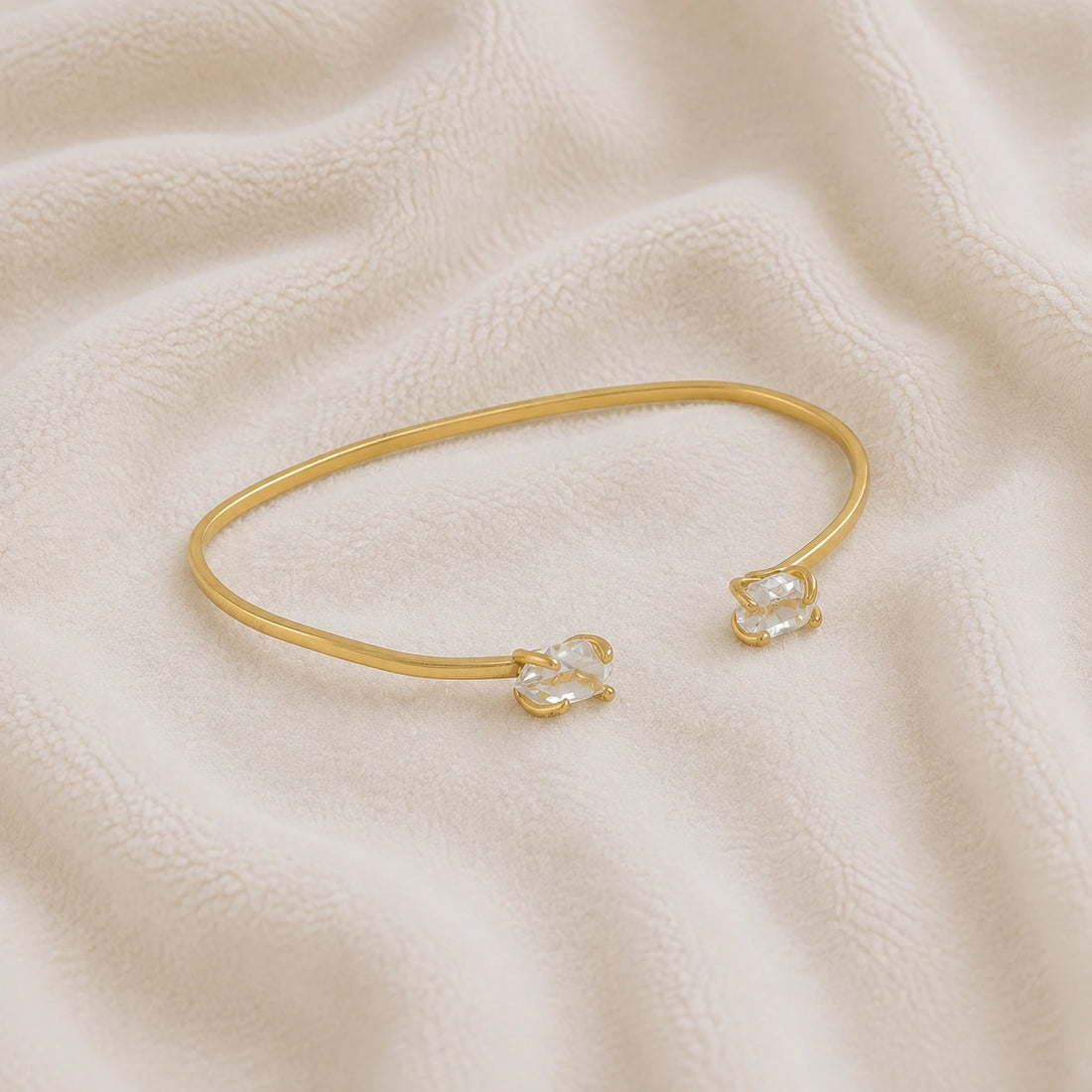 Crystal_bracelet_in_gold_plated_silver_with_two_raw_herkimer_stones_at_slight_angle_view_on_soft_fabric_background