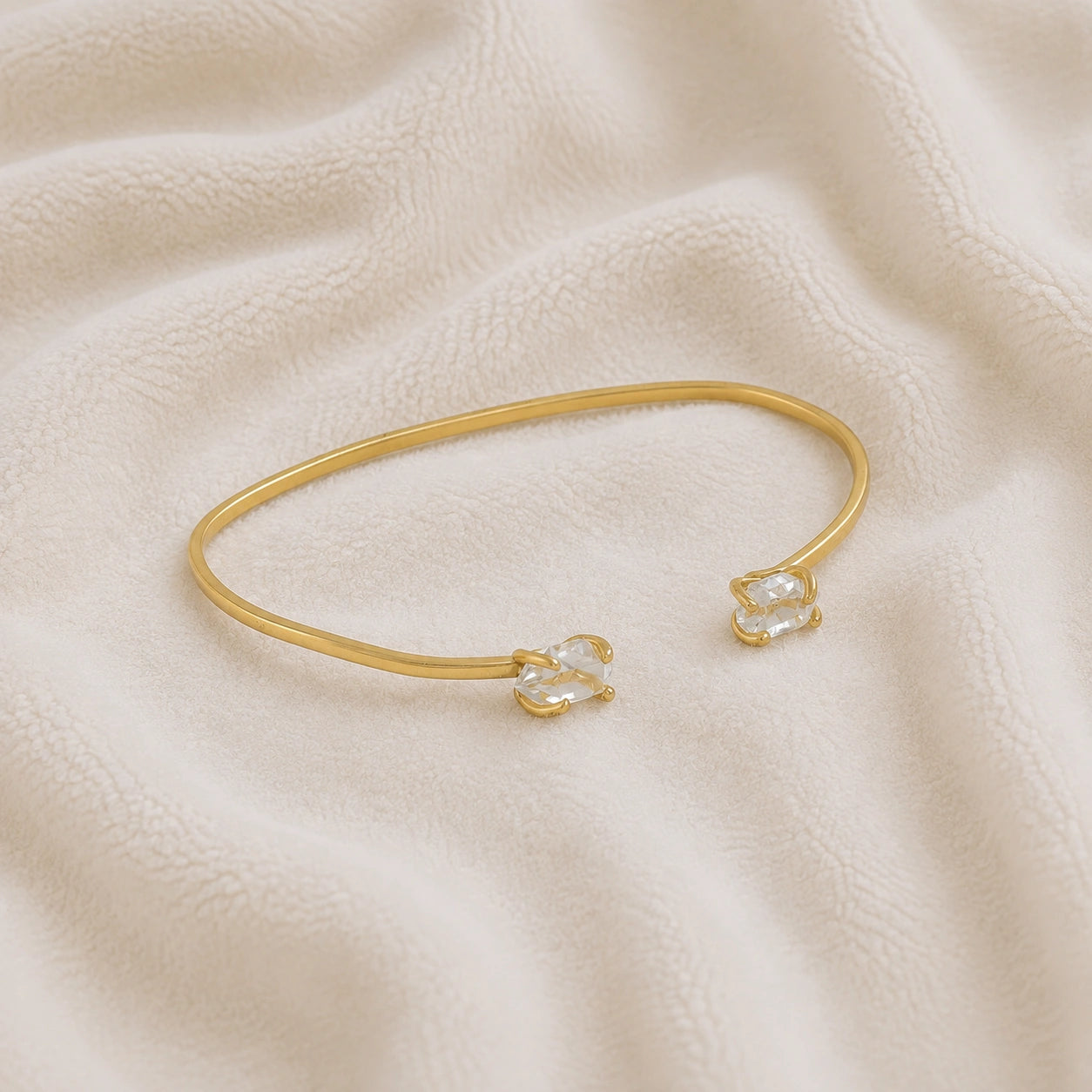 Crystal_bracelet_in_gold_plated_silver_with_two_raw_herkimer_stones_at_slight_angle_view_on_soft_fabric_background