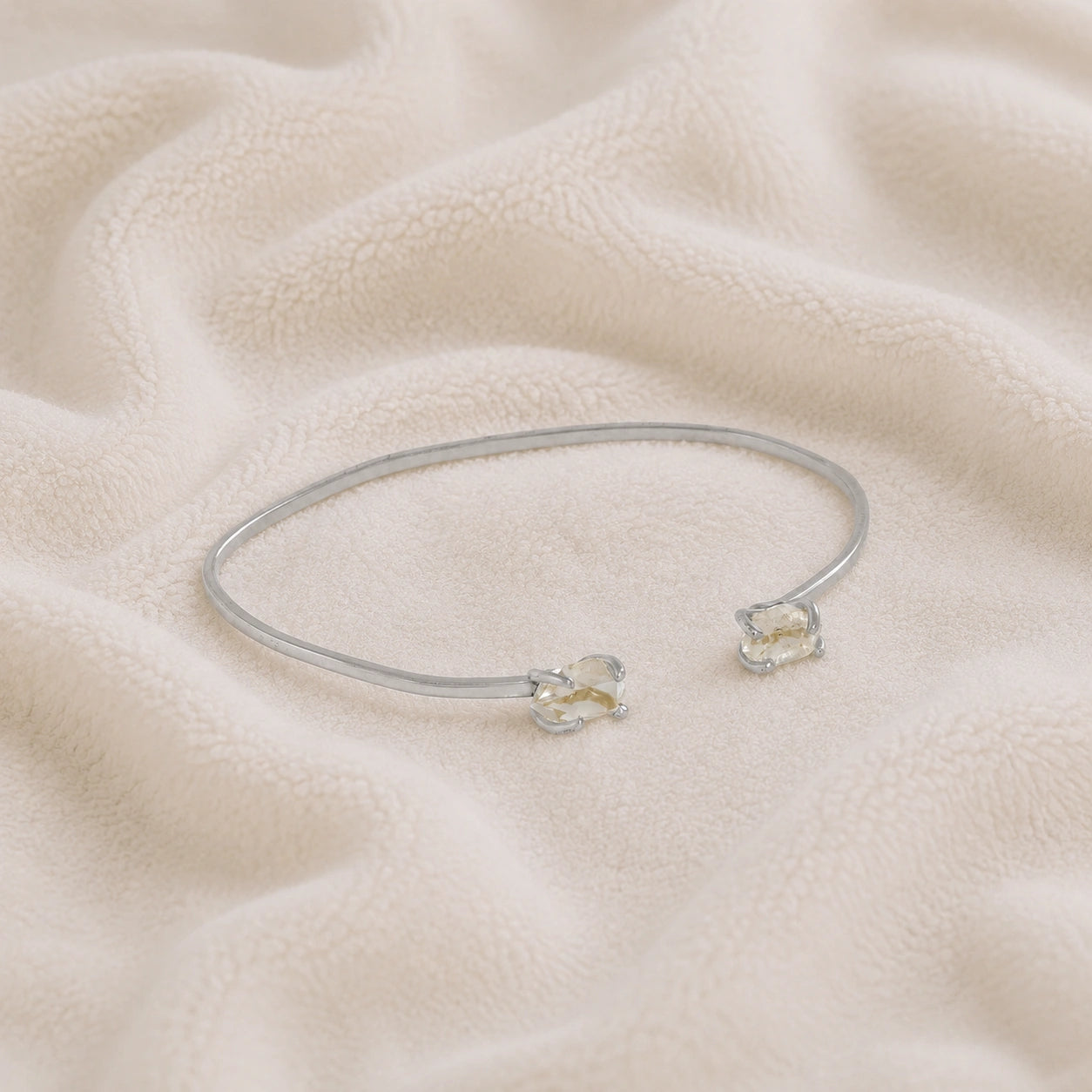 Crystal_bracelet_in_sterling_silver_with_two_raw_herkimer_stones_at_slight_angle_view_on_soft_fabric_background