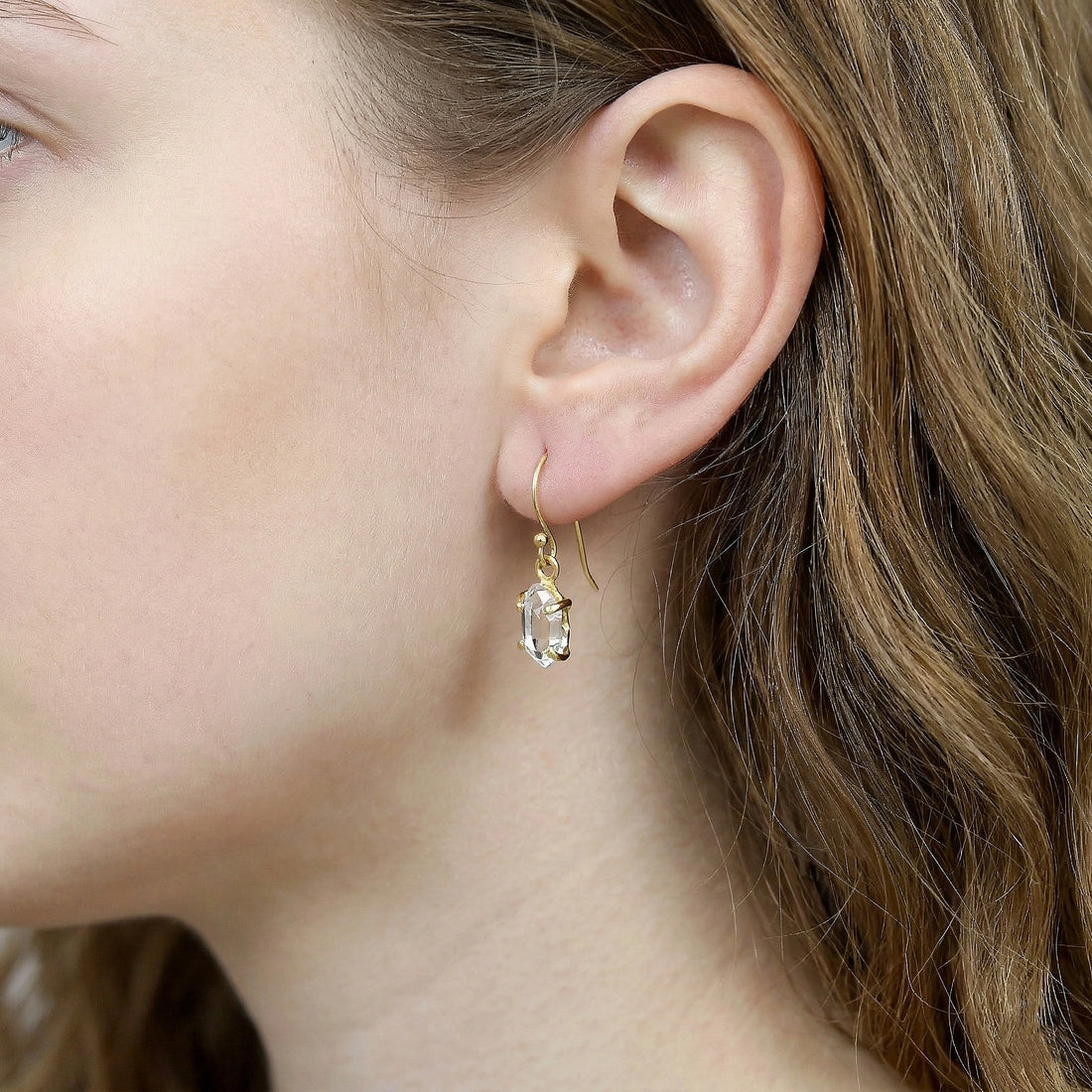 Crystal_earrings_in_gold_plated_silver_with_raw_stone_drop_design_in_front_angle_view_on_soft_white_fabric_background