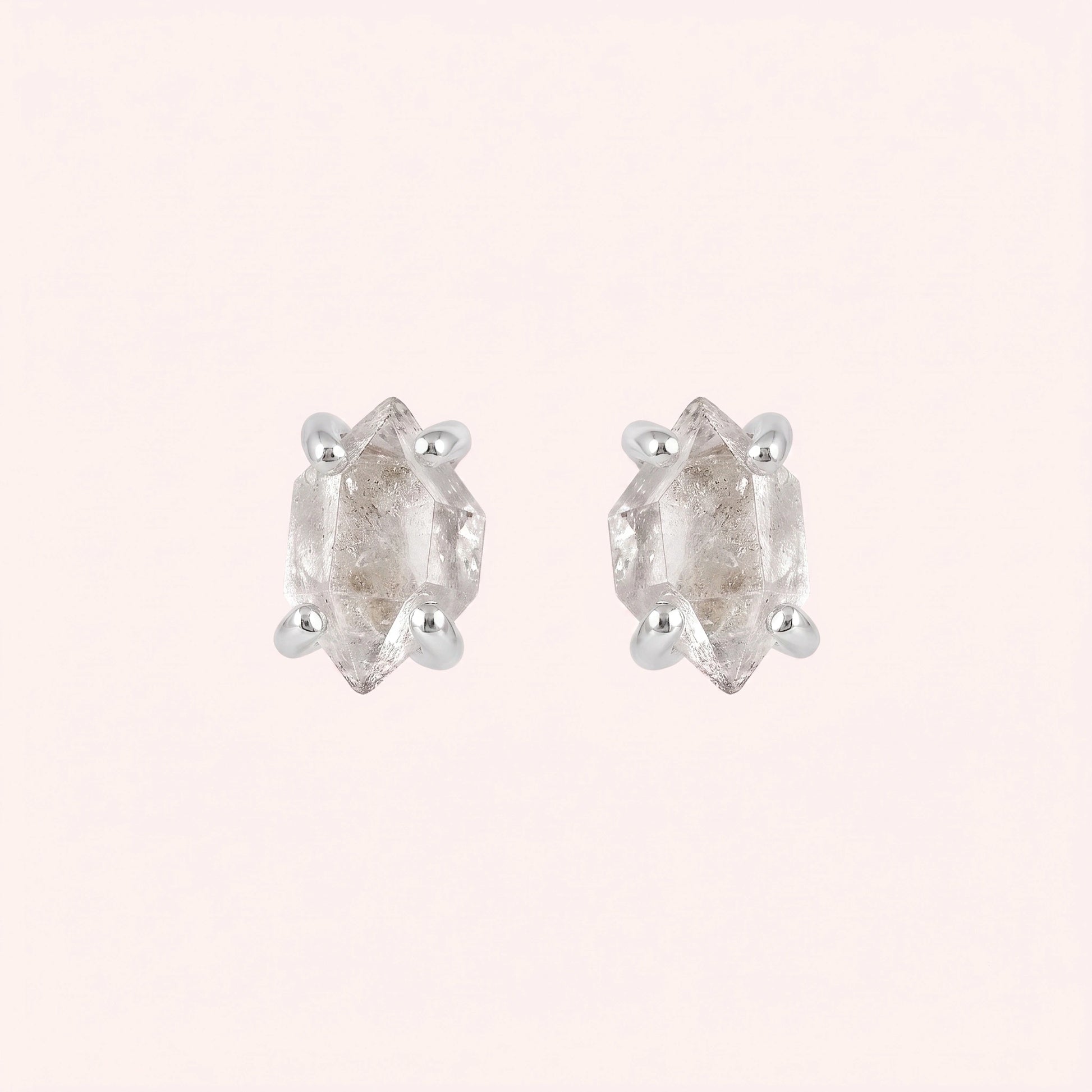 Crystal_earrings_in_sterling_silver_with_raw_herkimer_stone_at_front_angle_view_on_solid_pink_background