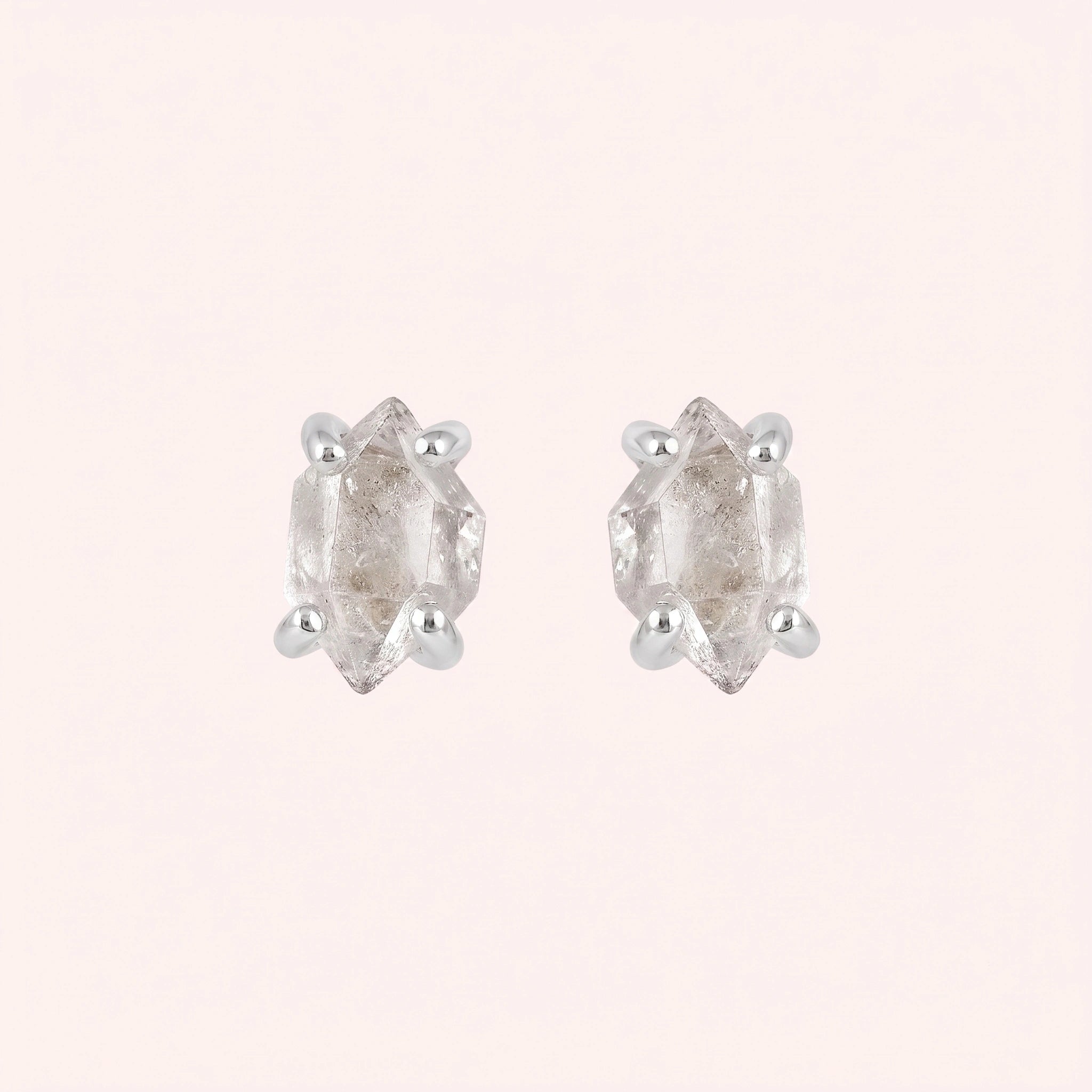 Crystal_earrings_in_sterling_silver_with_raw_herkimer_stone_at_front_angle_view_on_solid_pink_background