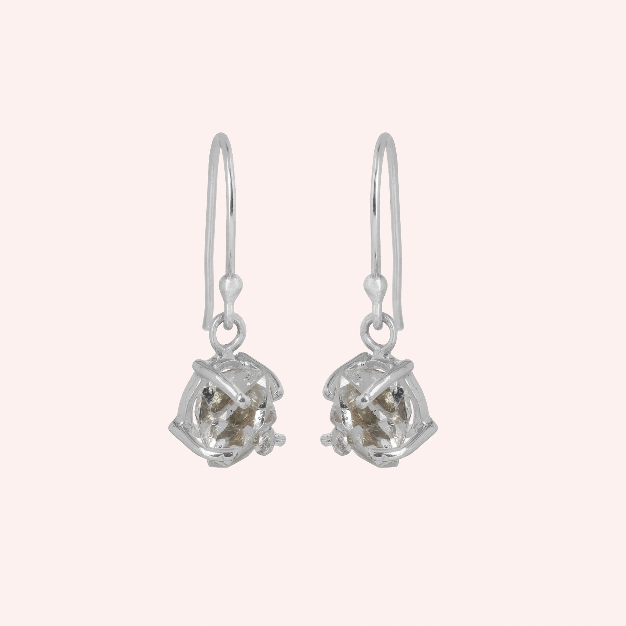 Crystal_earrings_in_sterling_silver_with_raw_stone_drop_design_in_slightly_angled_view_on_solid_pink_background