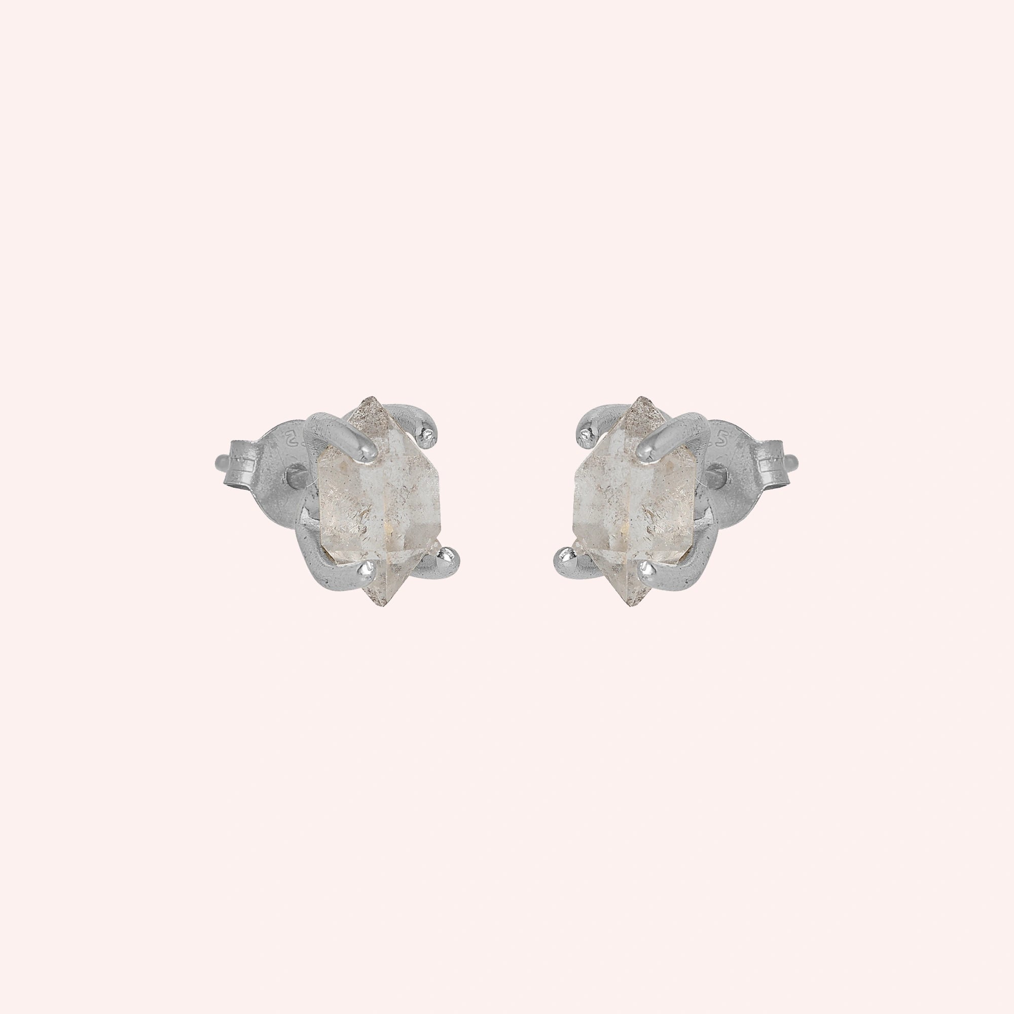 Crystal_earrings_in_sterling_silver_with_raw_herkimer_stone_at_slight_angle_view_on_solid_pink_background