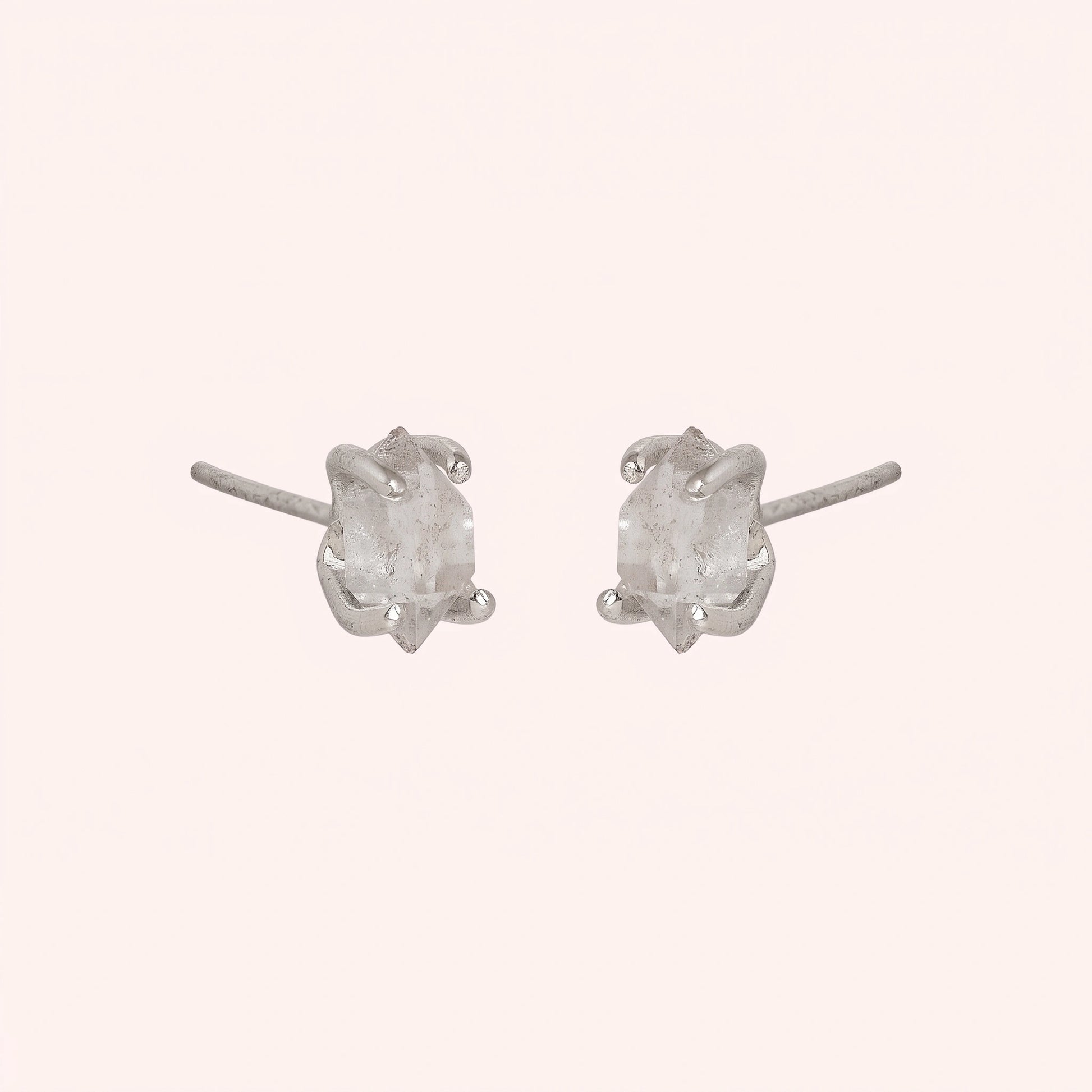 Crystal_earrings_in_sterling_silver_with_raw_herkimer_stone_at_slight_angle_view_on_solid_pink_background