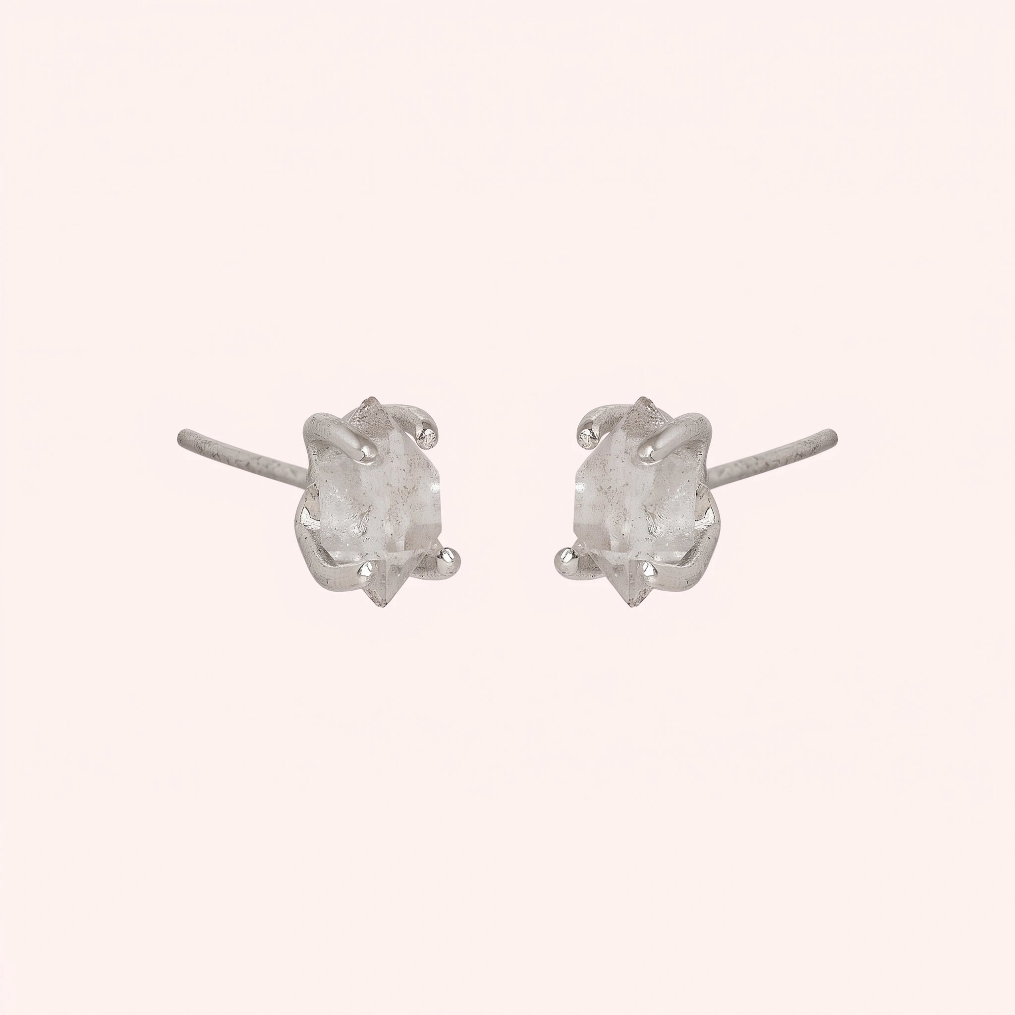 Crystal_earrings_in_sterling_silver_with_raw_herkimer_stone_at_slight_angle_view_on_solid_pink_background
