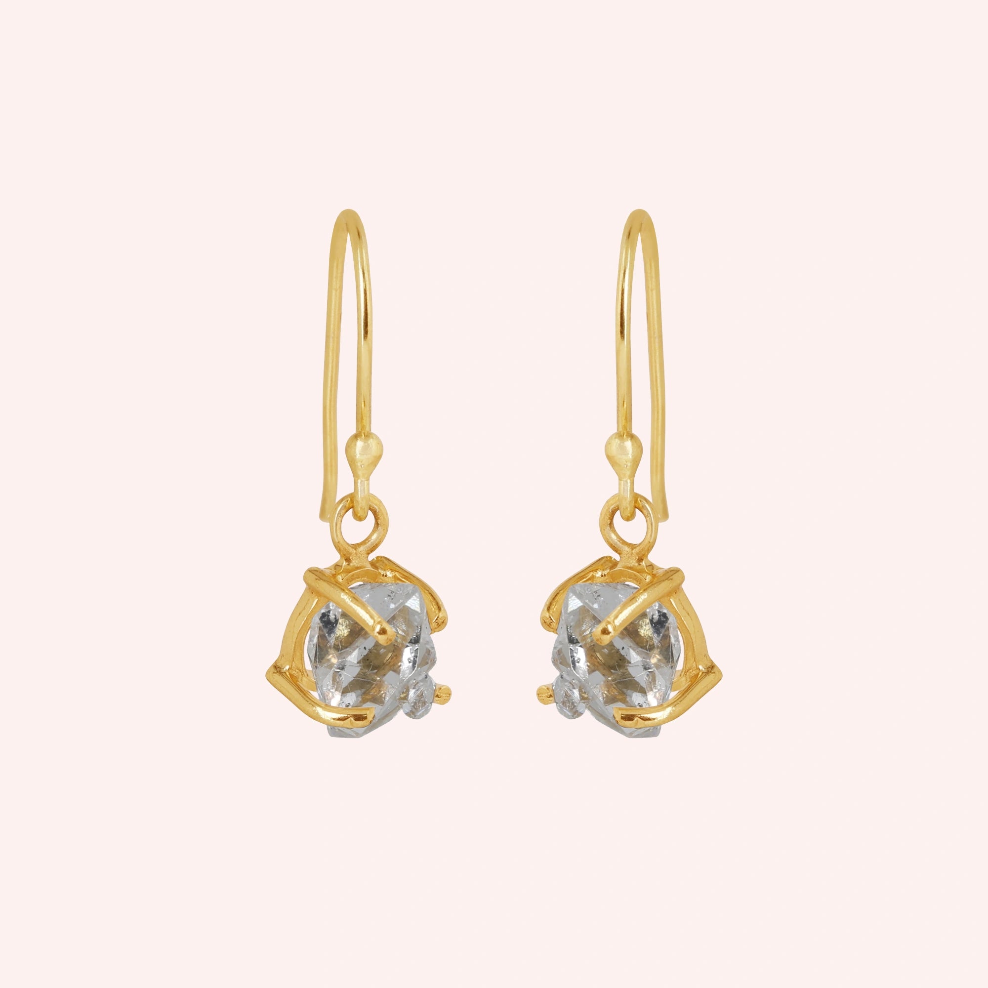 Crystal_earrings_in_gold_plated_silver_with_raw_stone_drop_design_in_slightly_angled_view_on_solid_pink_background