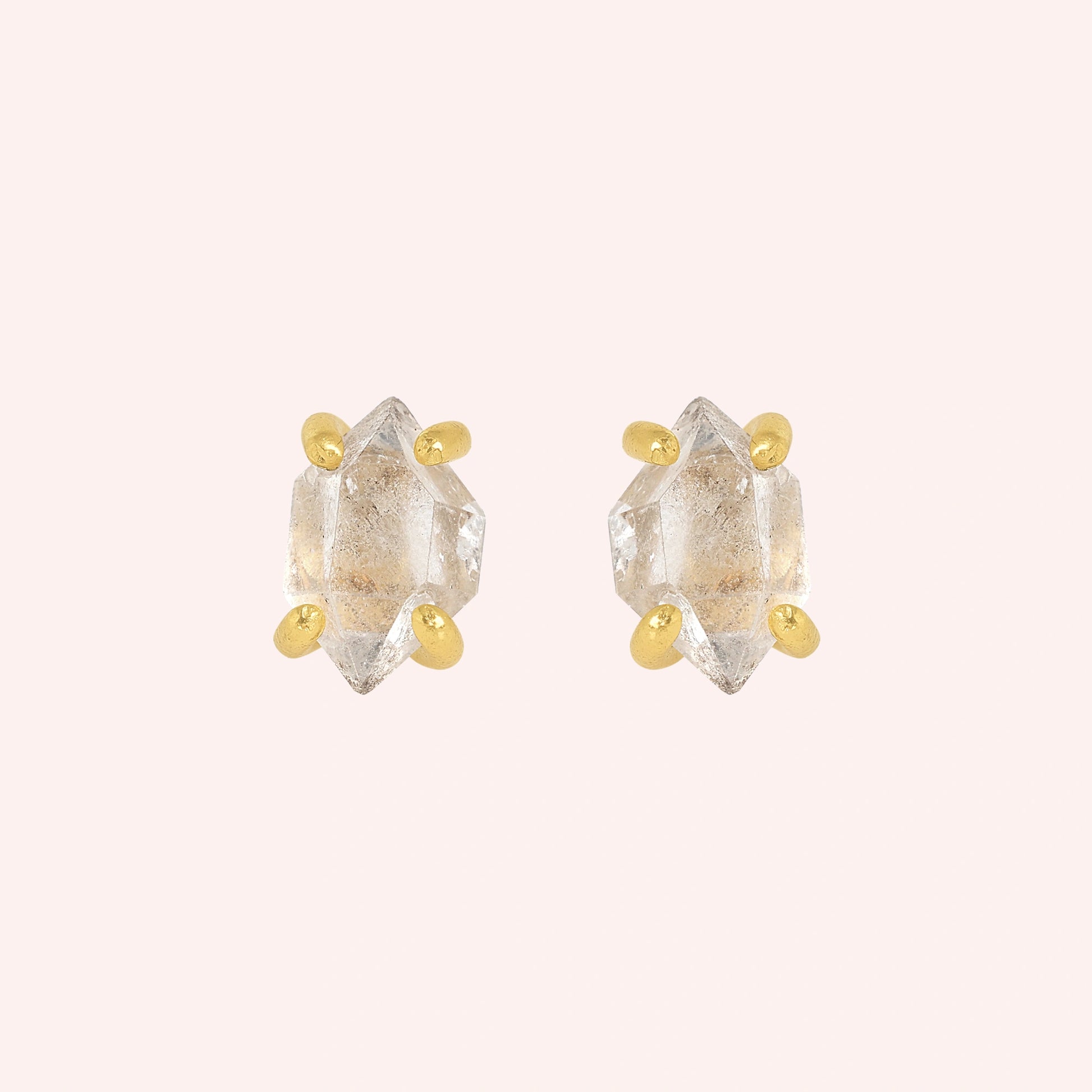 Crystal_earrings_in_gold_plated_silver_with_raw_herkimer_stone_at_front_angle_view_on_solid_pink_background