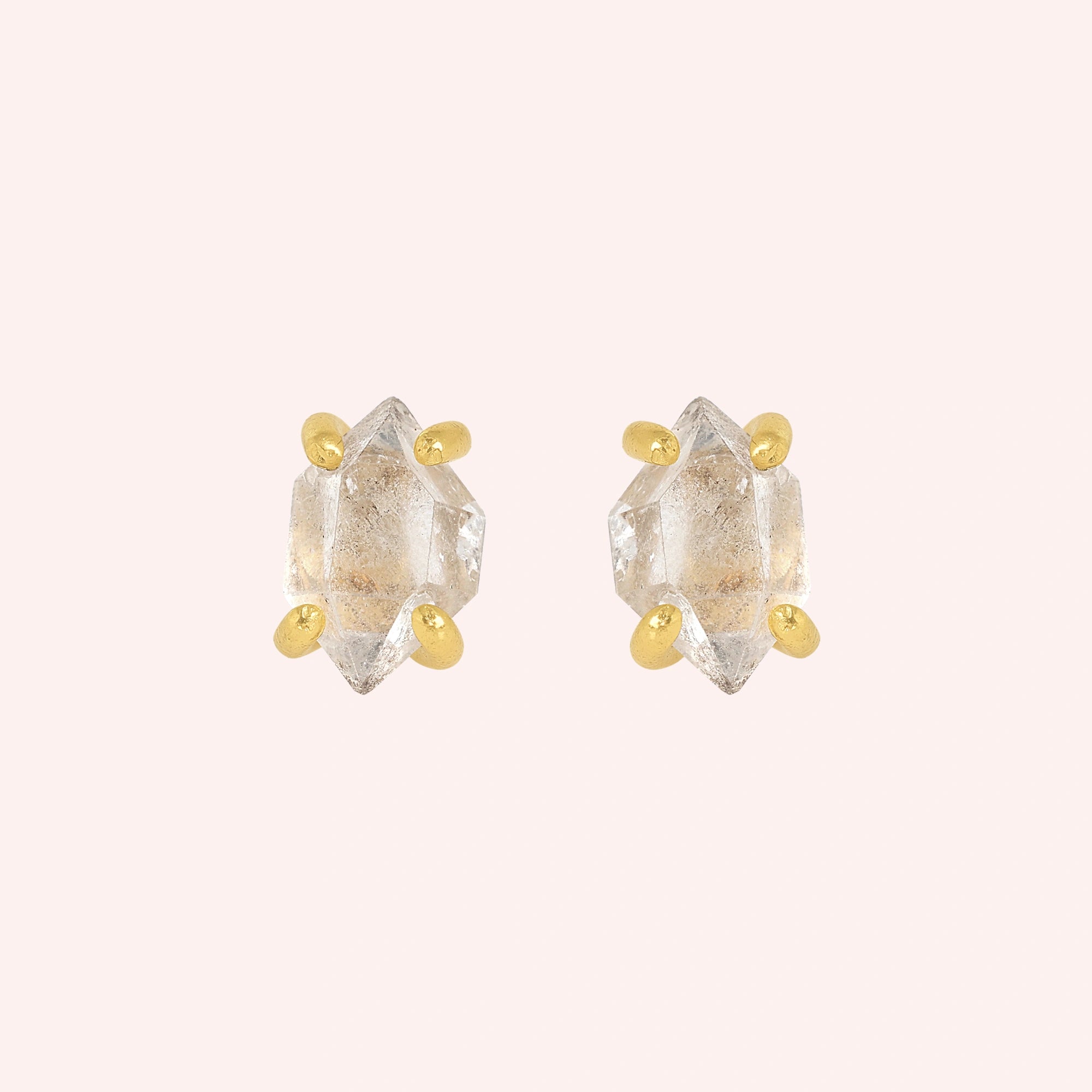 Crystal_earrings_in_gold_plated_silver_with_raw_herkimer_stone_at_front_angle_view_on_solid_pink_background