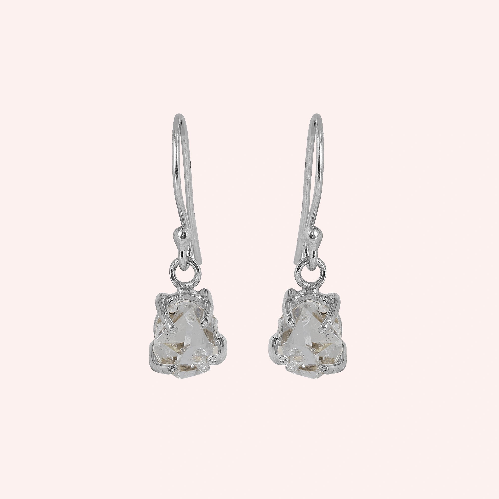 Crystal_earrings_in_sterling_silver_with_raw_stone_drop_design_in_front_angle_view_on_solid_pink_background