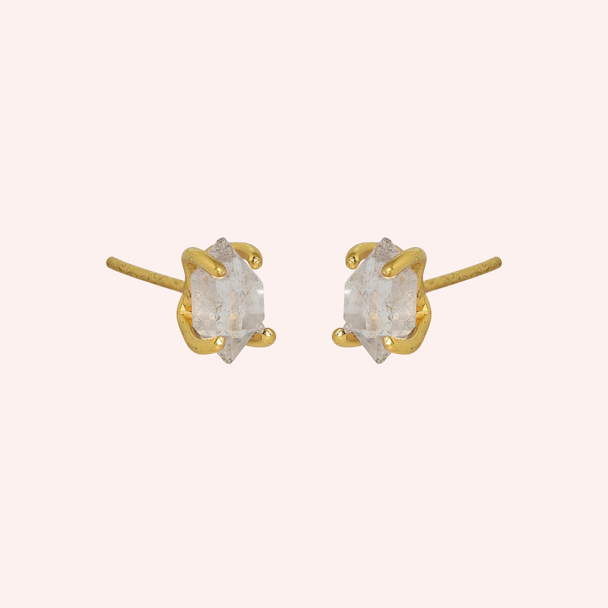 Crystal_earrings_in_gold_plated_silver_with_raw_herkimer_stone_at_slight_angle_view_on_solid_pink_background