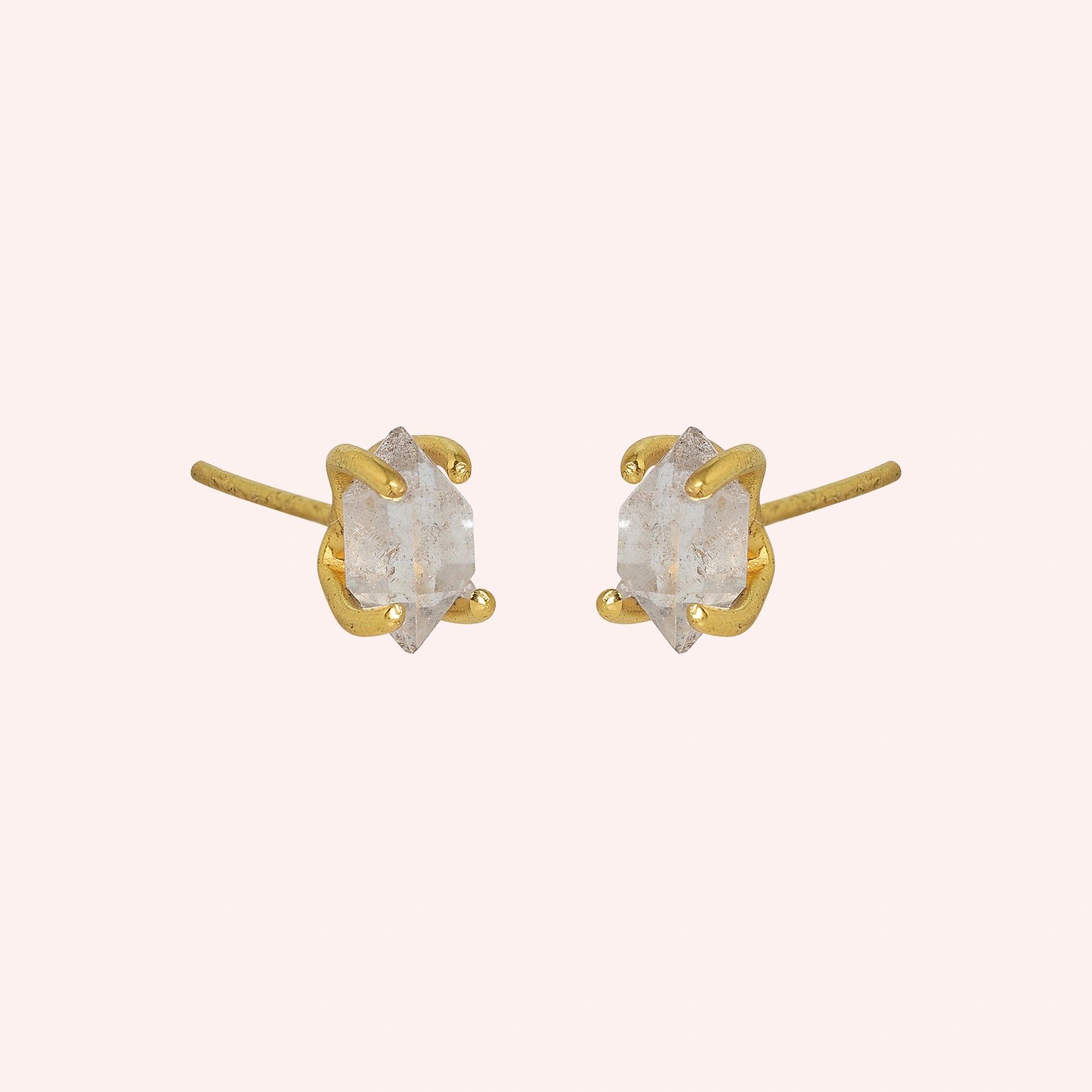 Crystal_earrings_in_gold_plated_silver_with_raw_herkimer_stone_at_slight_angle_view_on_solid_pink_background