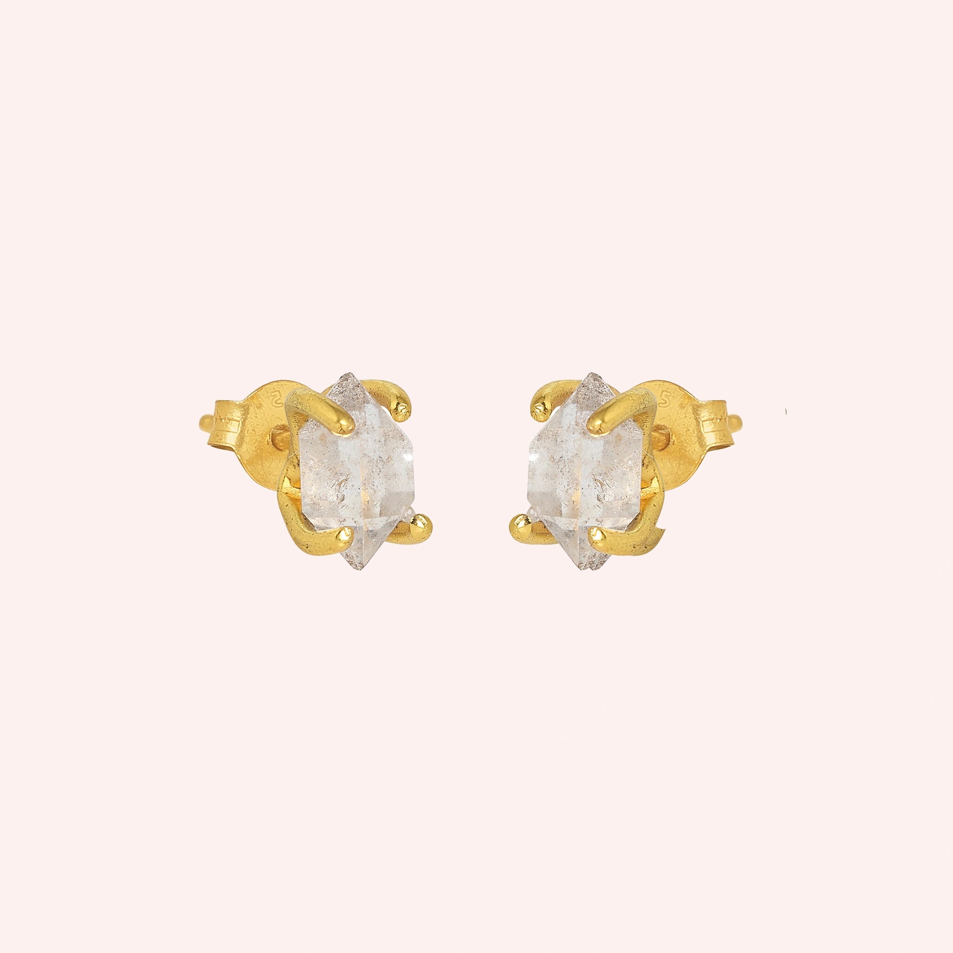 Crystal_earrings_in_gold_plated_silver_with_raw_herkimer_stone_at_slight_angle_view_on_solid_pink_background