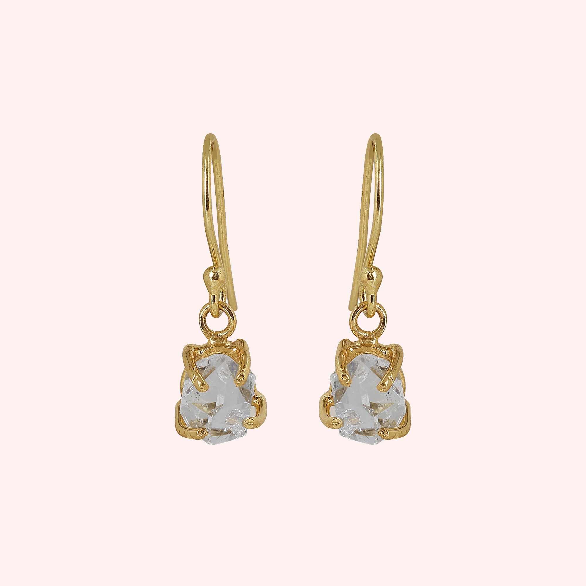 Crystal_earrings_in_gold_plated_silver_with_raw_stone_drop_design_in_front_angle_view_on_solid_pink_background