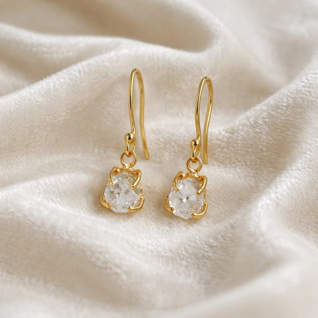 Crystal_earrings_in_gold_plated_silver_with_raw_stone_drop_design_in_front_angle_view_on_soft_white_fabric_background