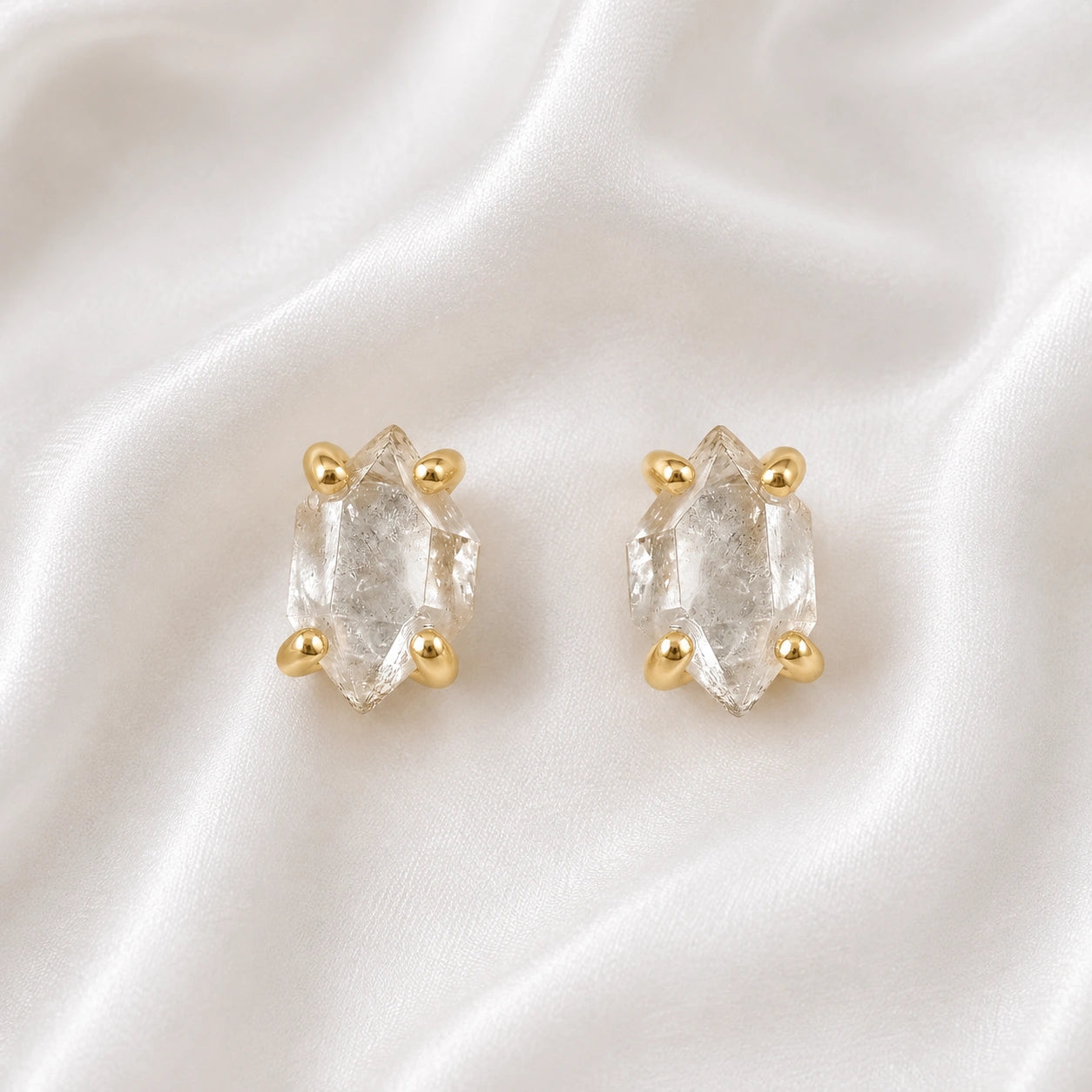 Crystal_earrings_in_gold_plated_silver_with_raw_herkimer_stone_at_front_angle_view_on_soft_fabric_background